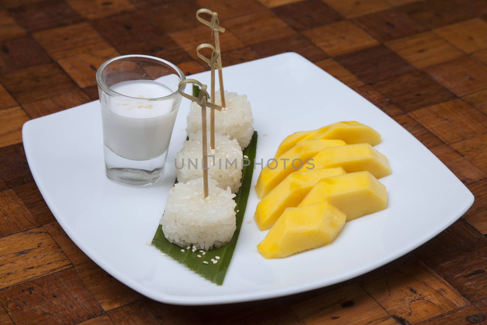Mango sticky rice topped with beans topped with coconut cream in a dish.