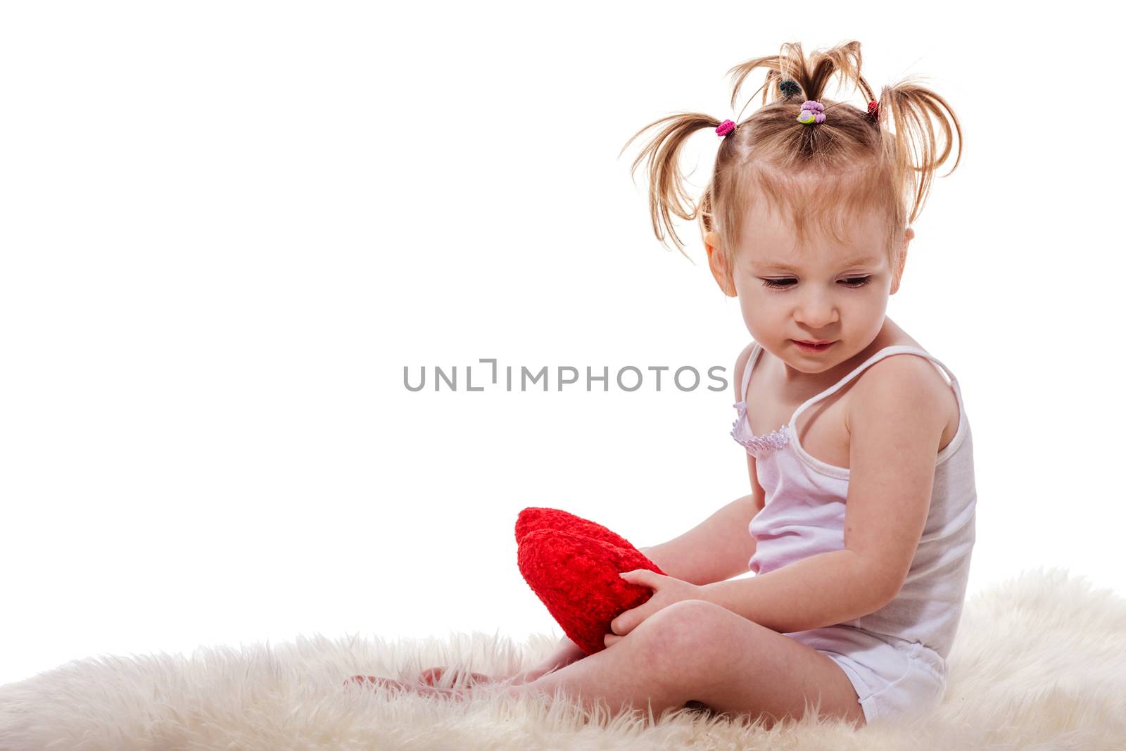 Adorable little girl sitting in a warm bed isolated on white
