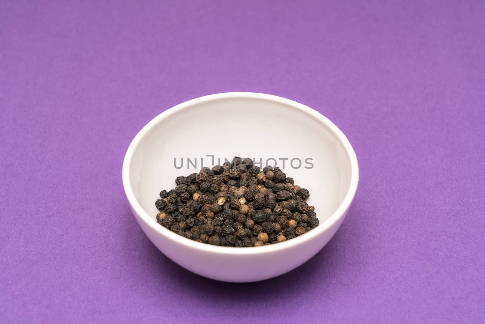 black pepper in a bowl on a colored background
