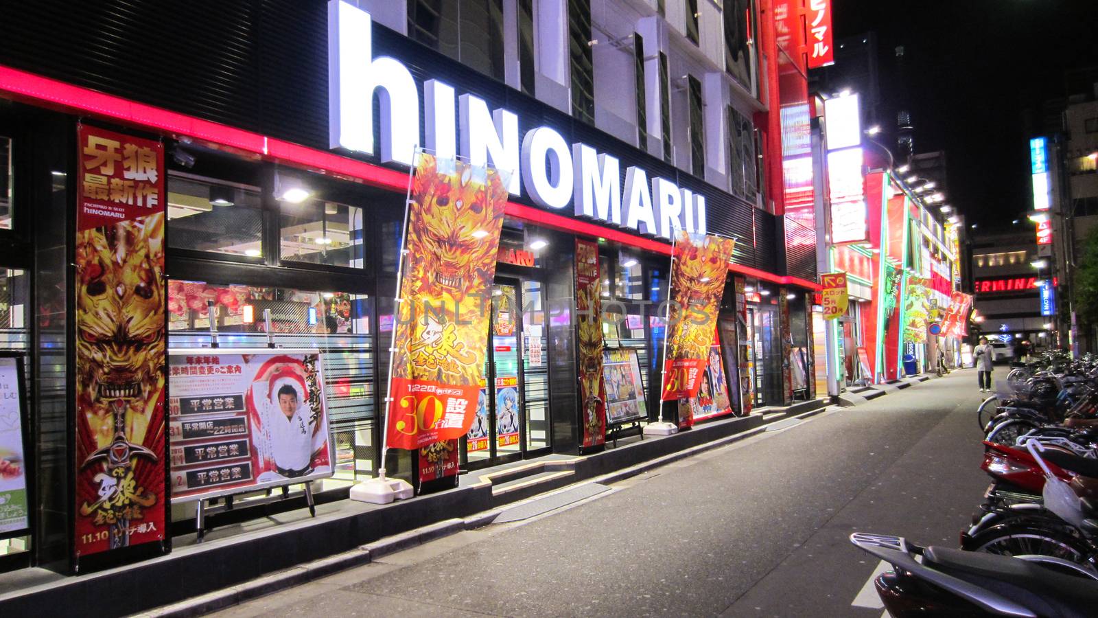 TOKYO, JAPAN - JANUARY 2, 2015: Japanese bright lighted establishment on a street in Tokyo at night with lots of advertisement and some scooters parked in front on January 2, 2015 in Tokyo, Japan.