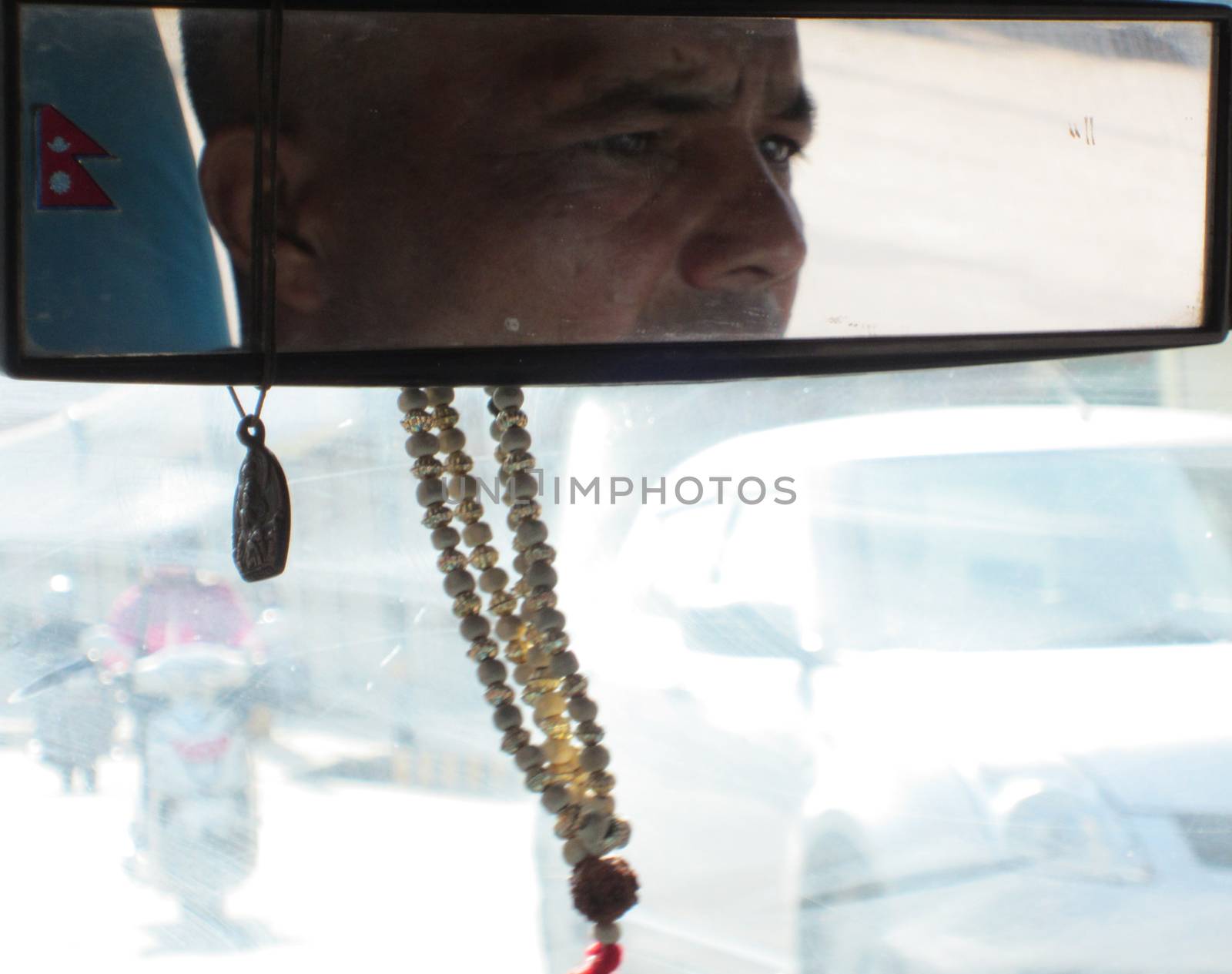 KATHMANDU, NEPAL - APRIL 1, 2015: The Picture is taken from the rear bench inside of a cap  showing the Nepalese driver reflecting in the mirror and some busy traffic through the front window during a dusty ride on April 1, 2015 in Kathmandu, Nepal.