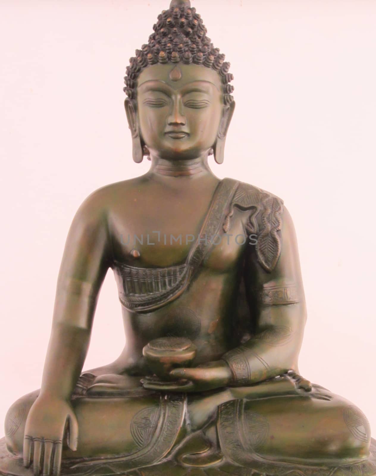 Golden, closed eye Buddha statue is sitting in front of a white background.