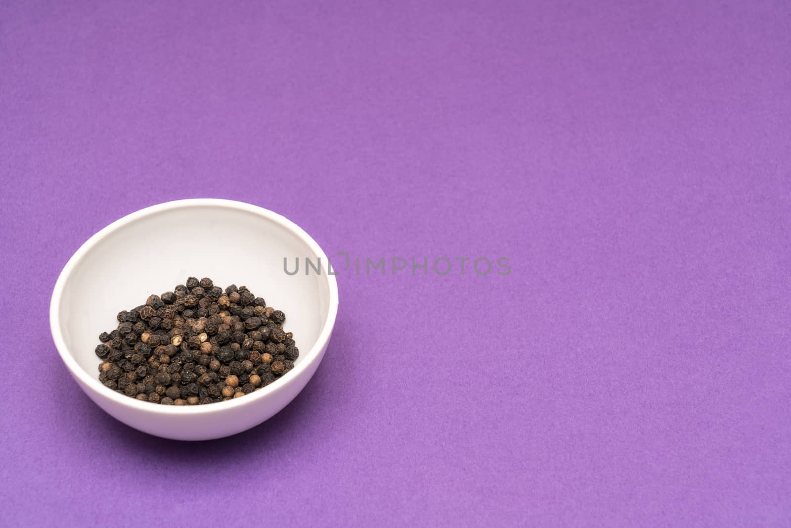 black pepper in a bowl on a colored background