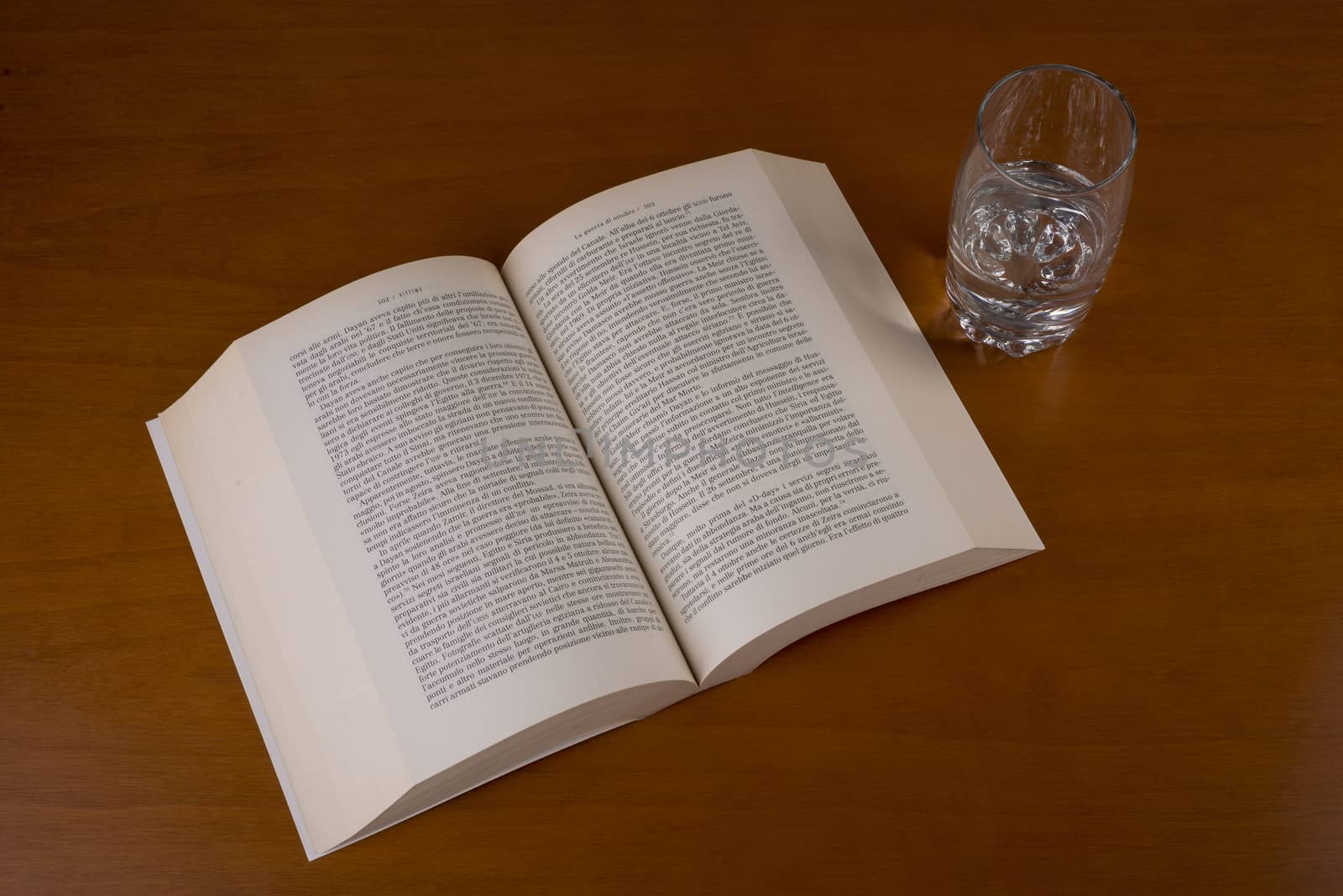 an open book with a glass of water alongside