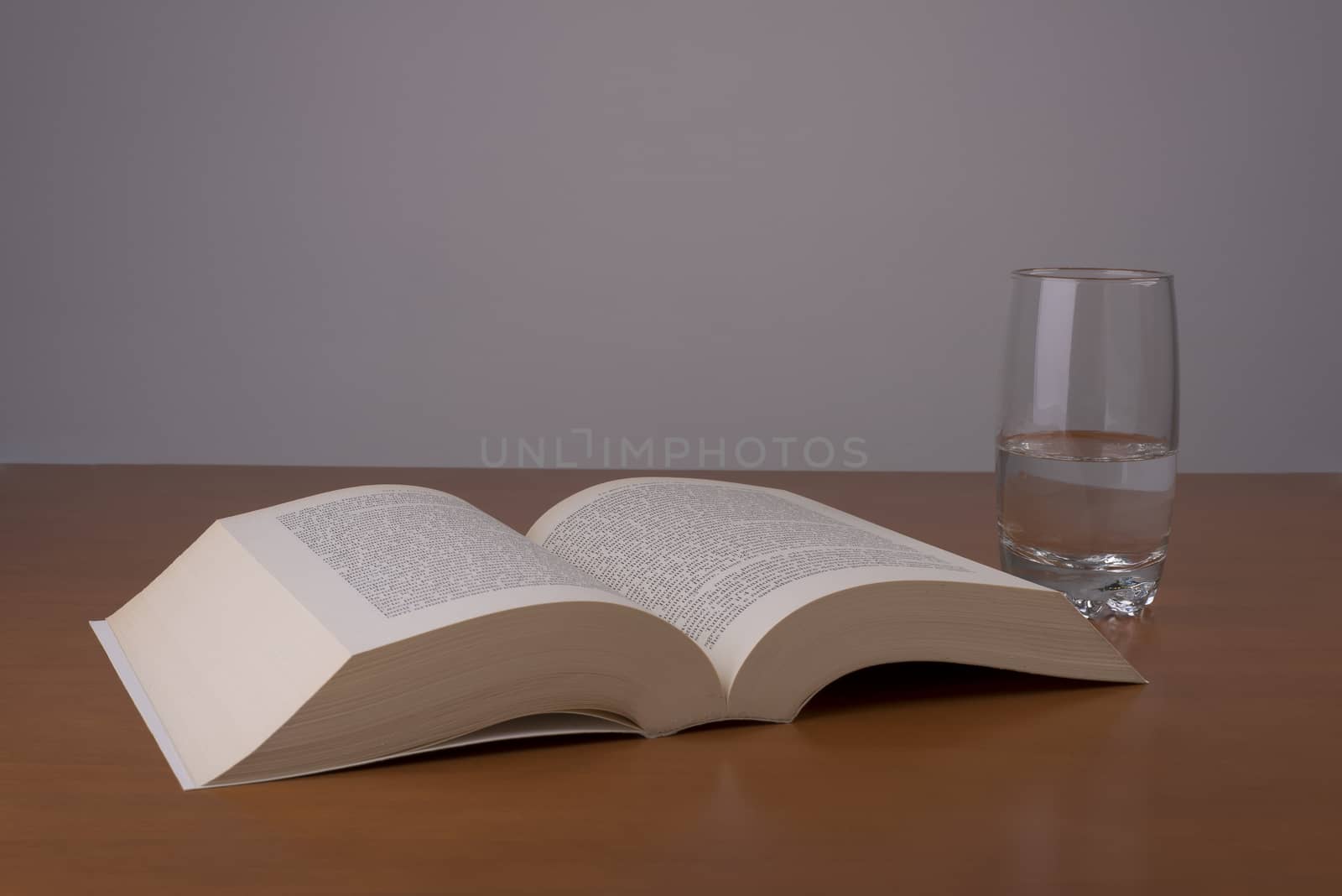 an open book with a glass of water alongside