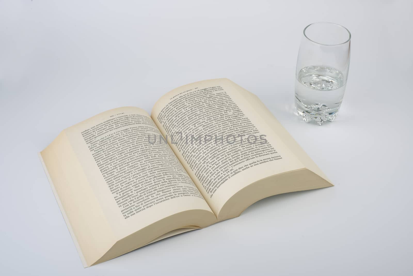 an open book with a glass of water alongside