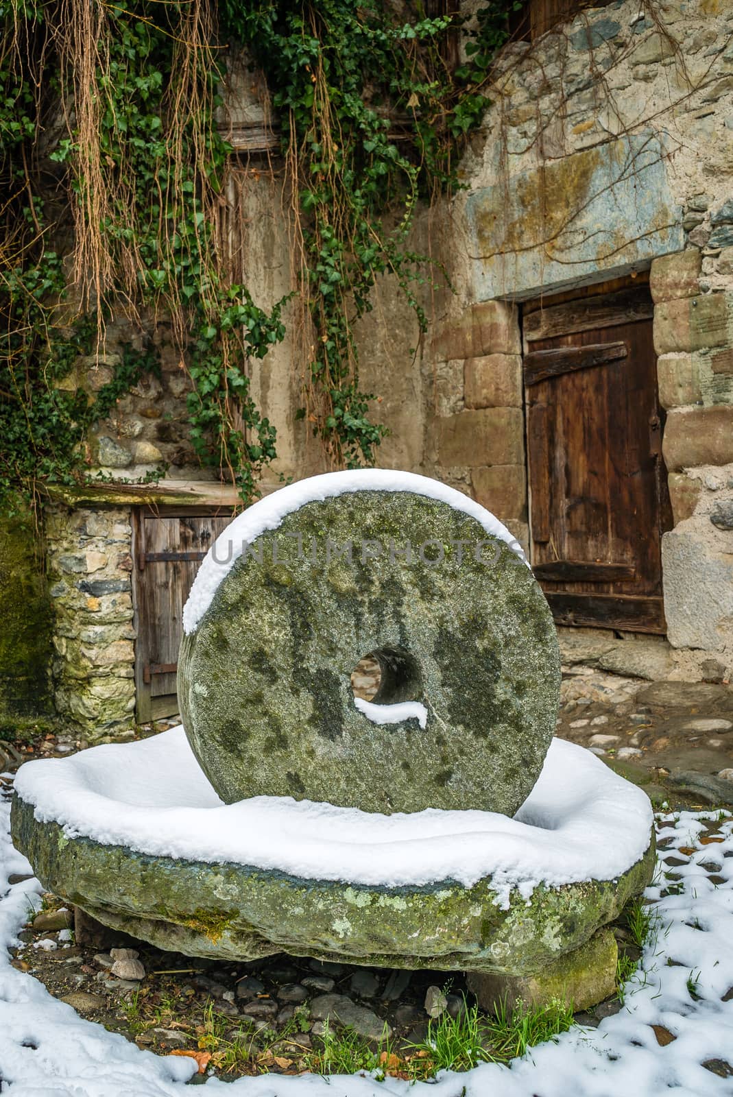 Old grinding wheel covered with snow in the winter