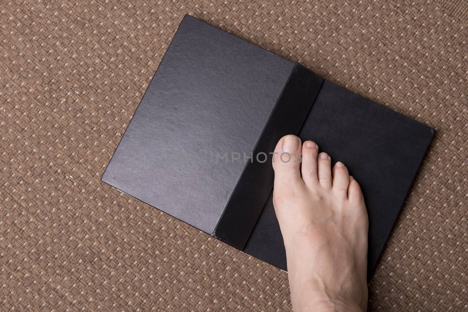 a book on the carpet with a barefoot foot above