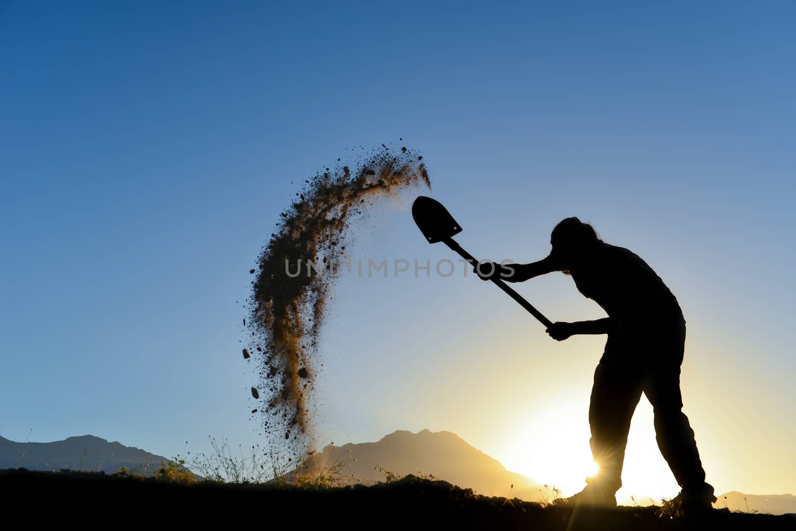 silhouette of a man who the soil with a shovel