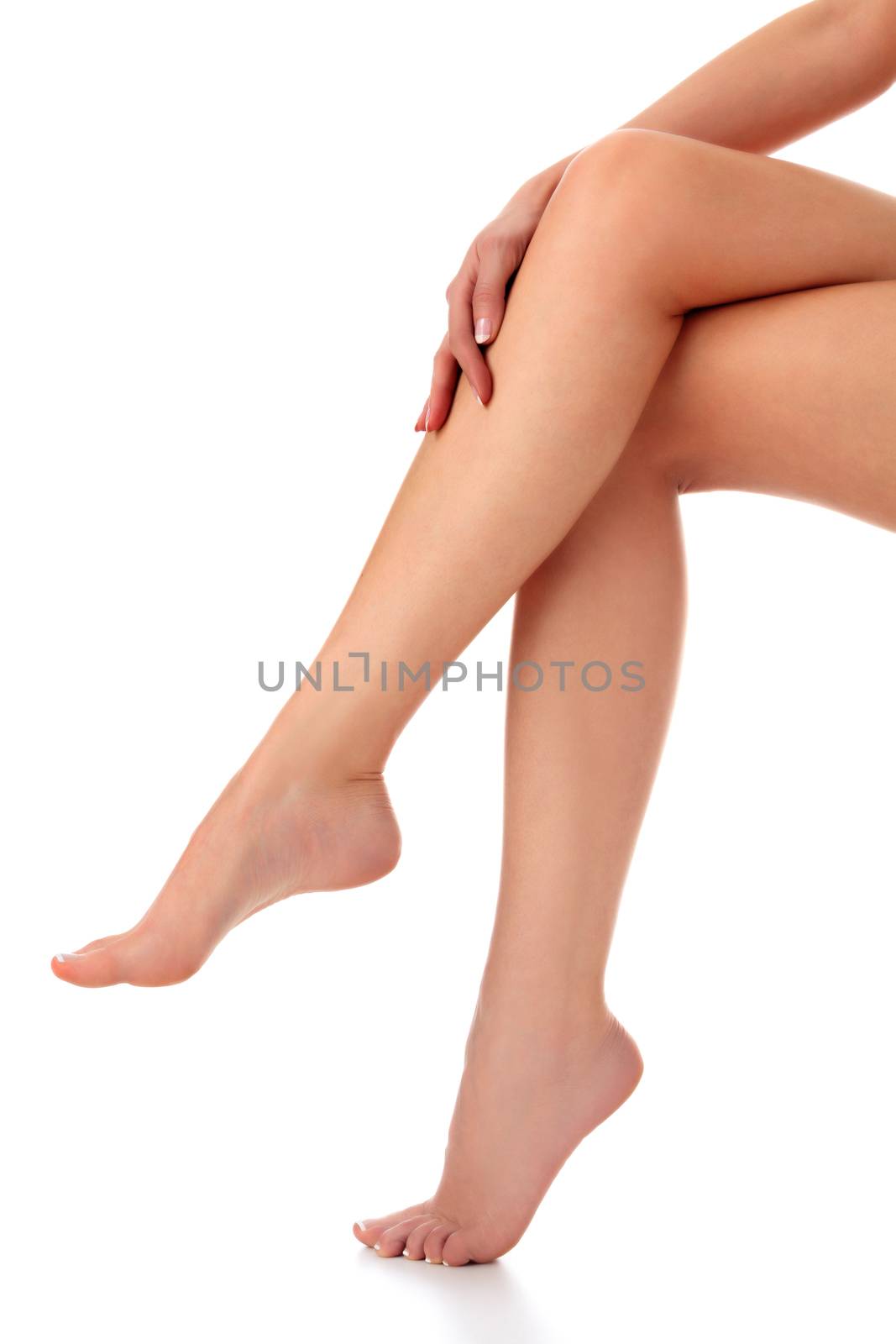 Closeup shot of beautiful female legs and hands. Woman touches her smooth skin with french manicured hands. Isolated on white background