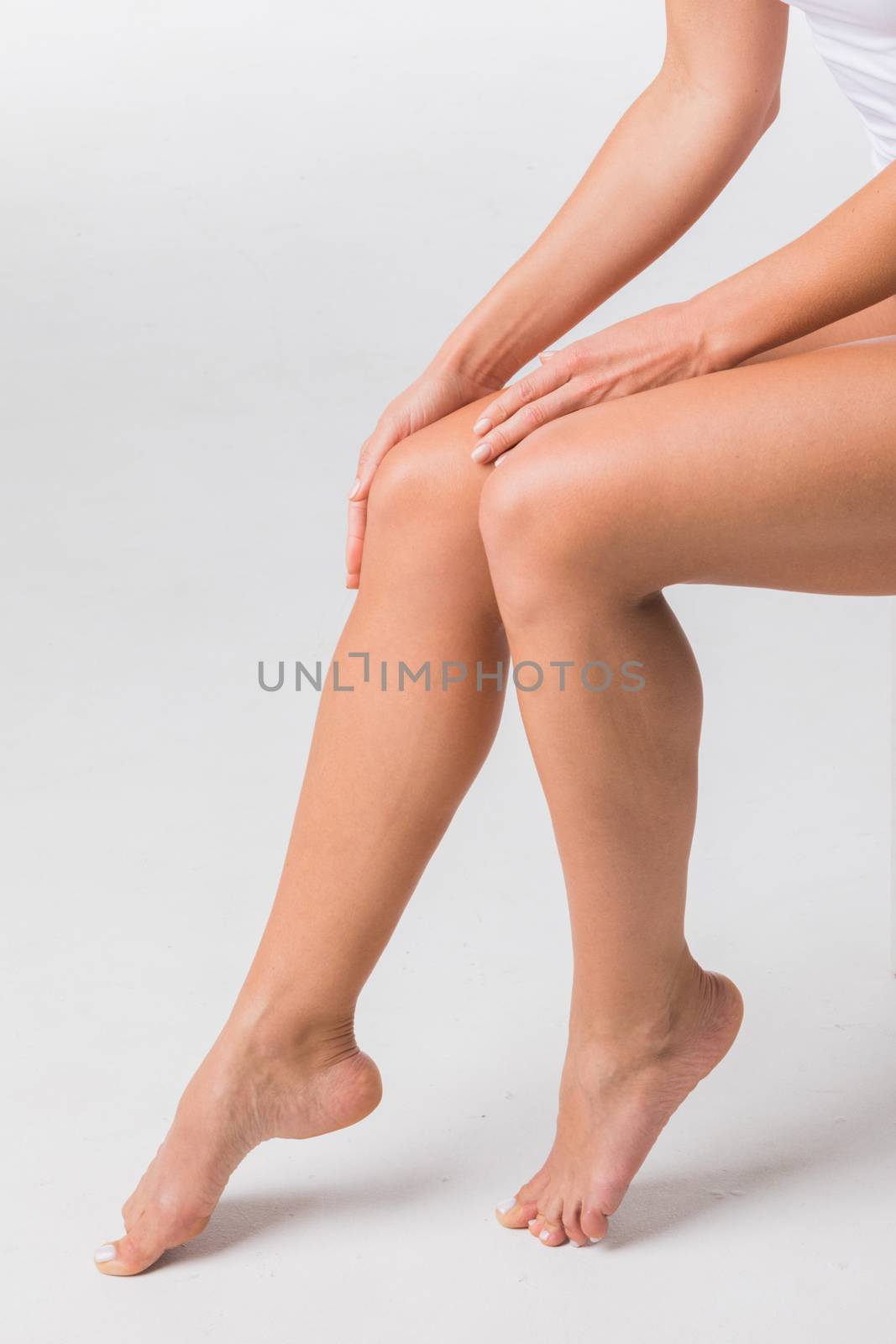 Young beautiful woman touching legs on white background