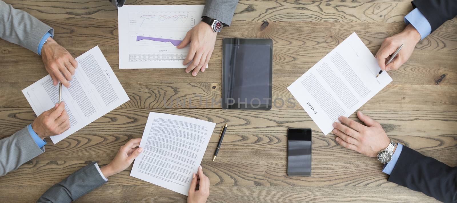 Business people discuss contract sitting around office table, top view