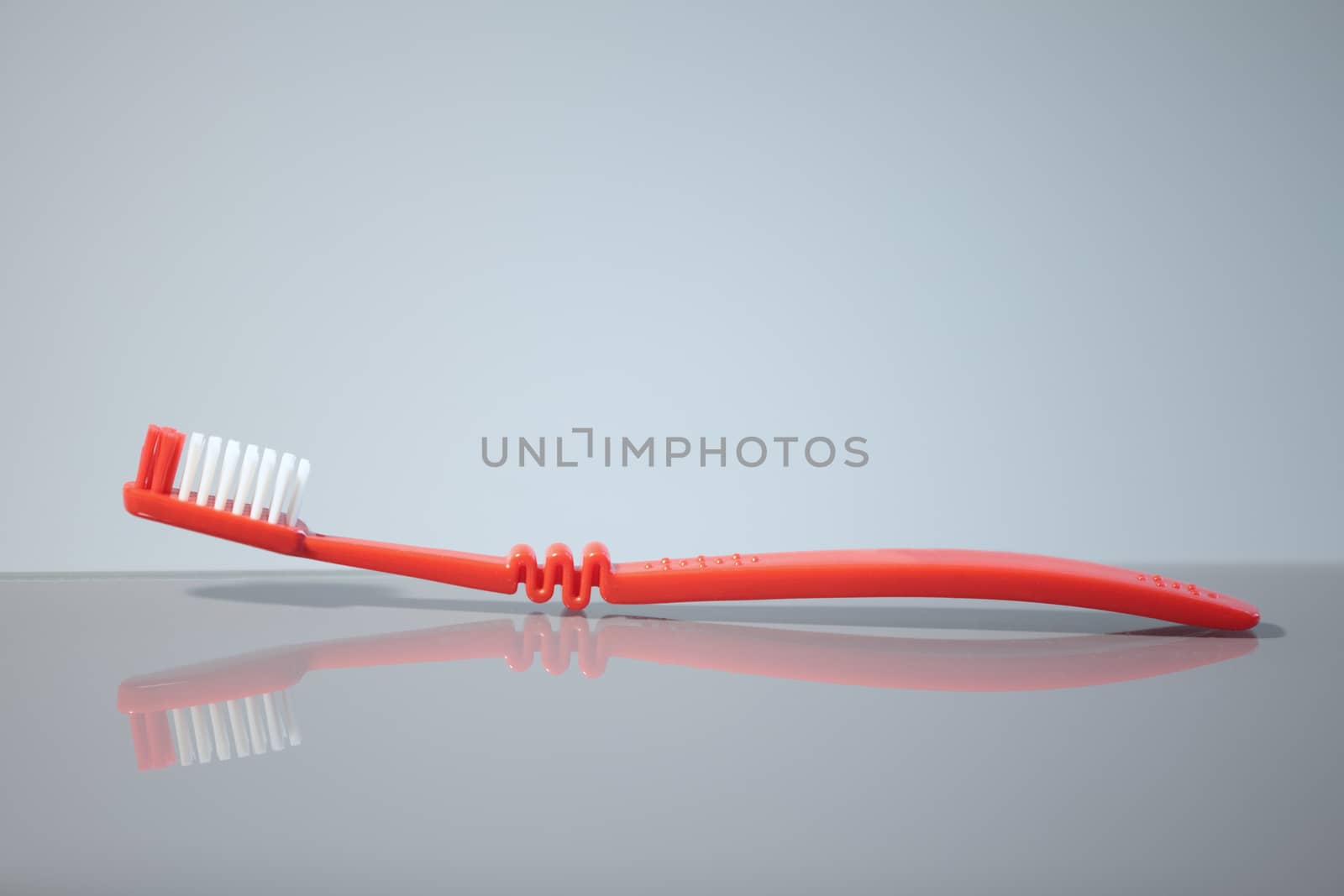 Red toothbrush with reflection, macro shot,  by mrivserg