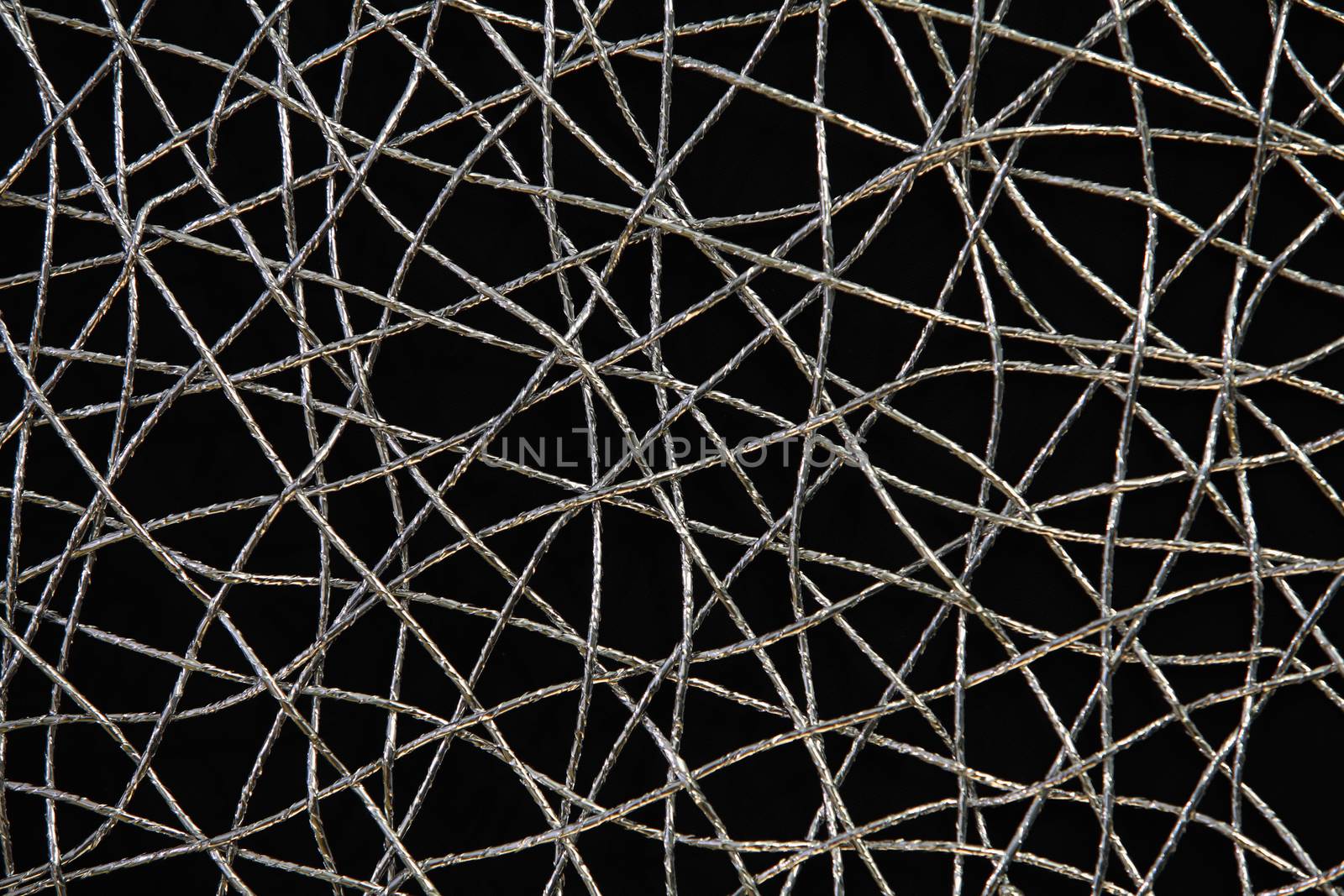 Chaotic weave of silver threads on black, abstract background