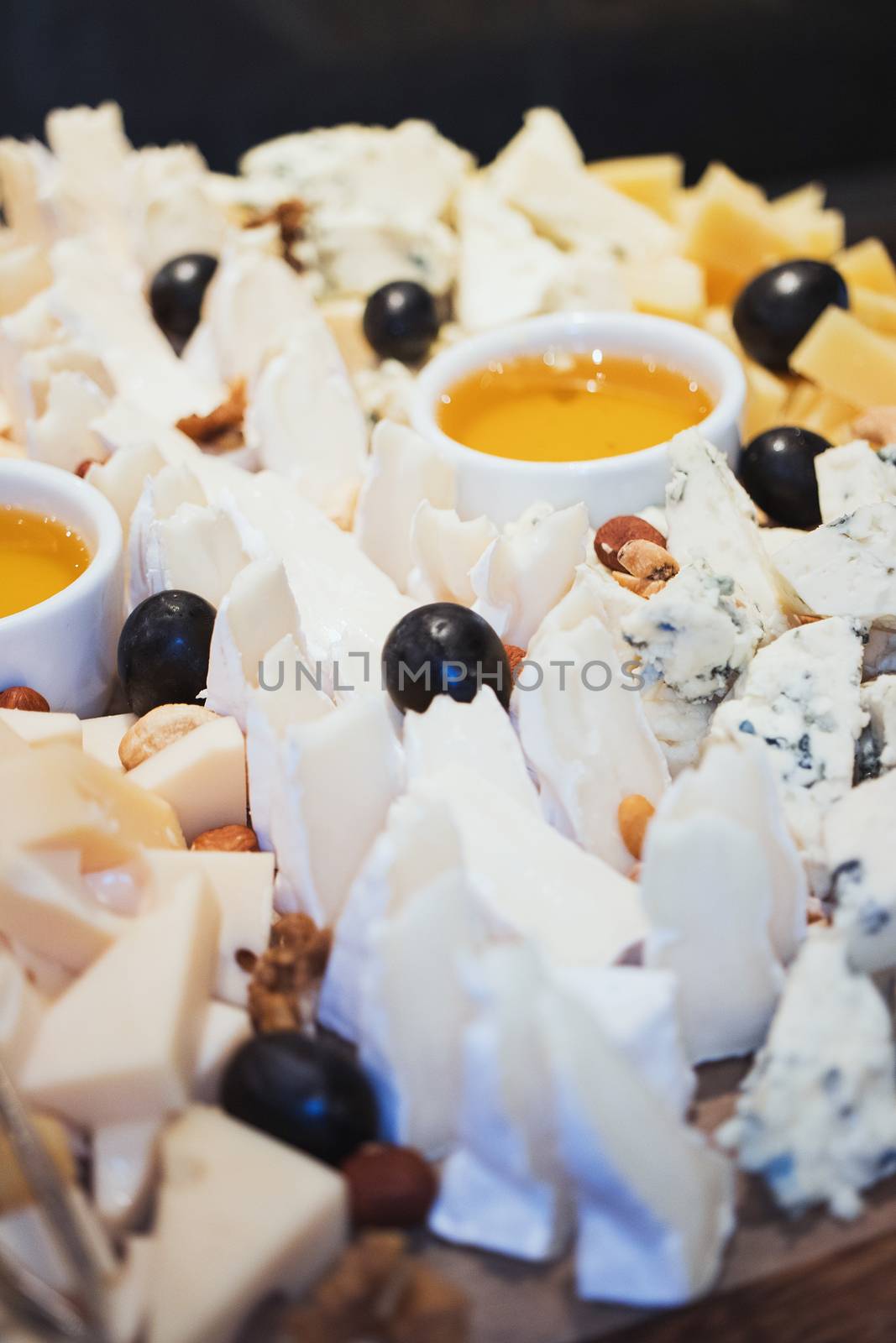 Cheese plate. Assortment of cheese with walnuts and honey from honey dipper on white wood serving board over white concrete texture background. Top view with space. Appetizer theme by 3KStudio