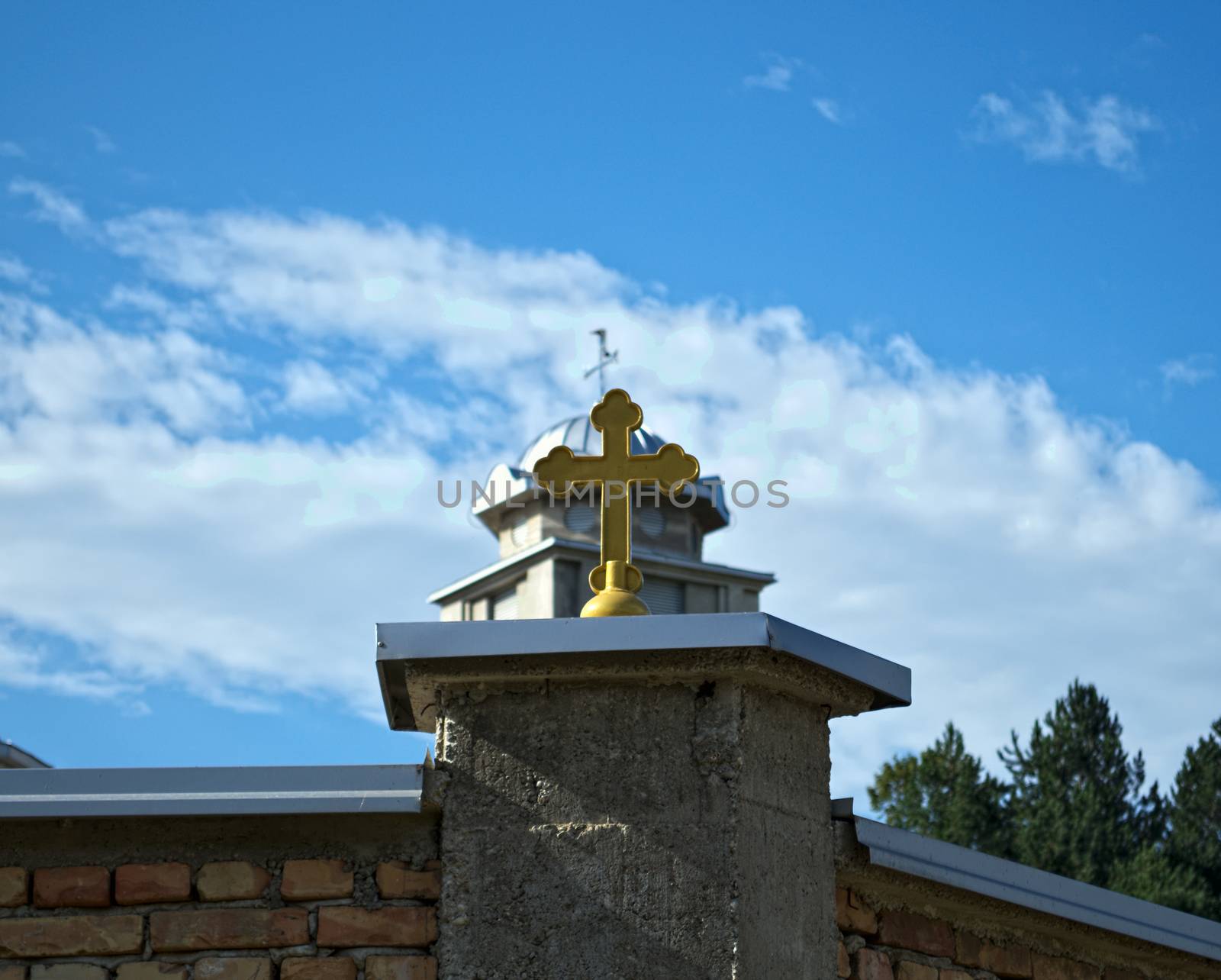 Cross on monastery fence and church dome in background