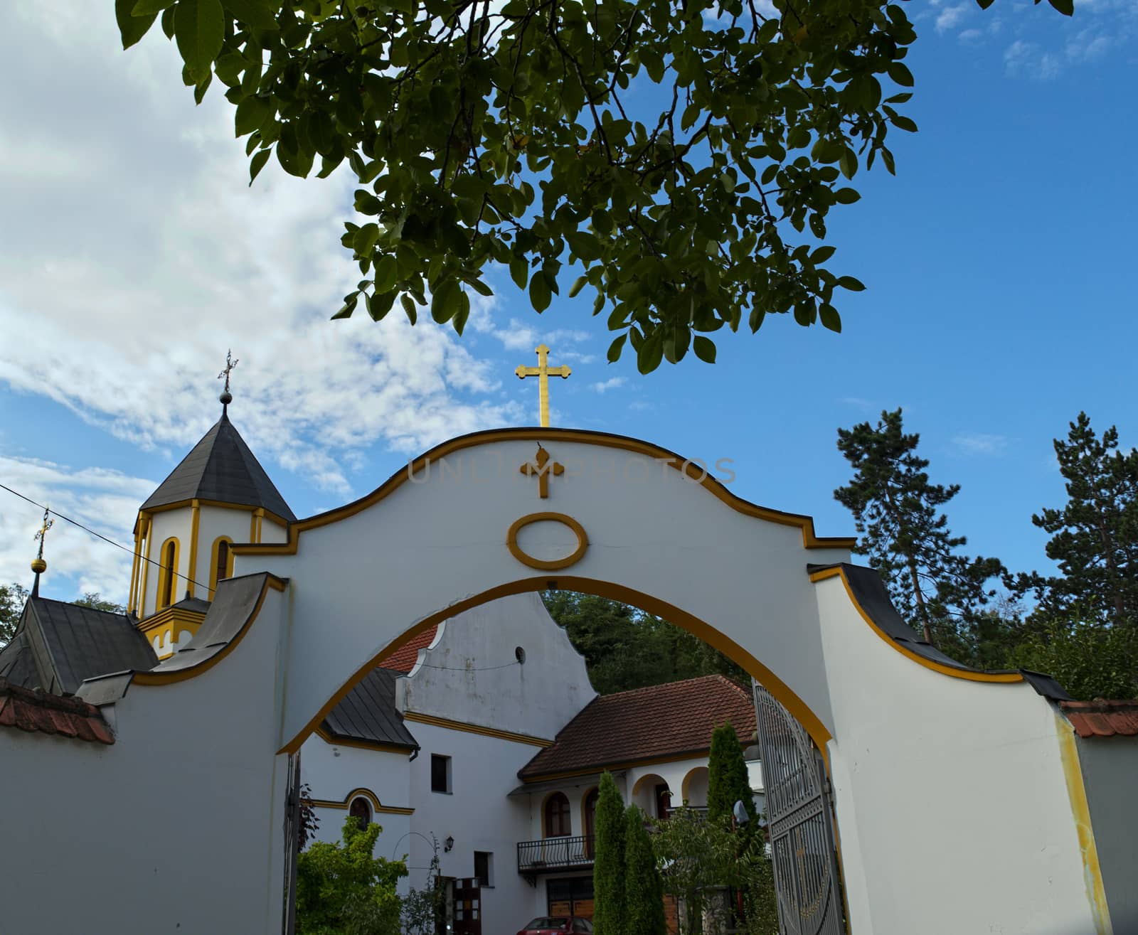 Entrance to a monastery and church tower in background