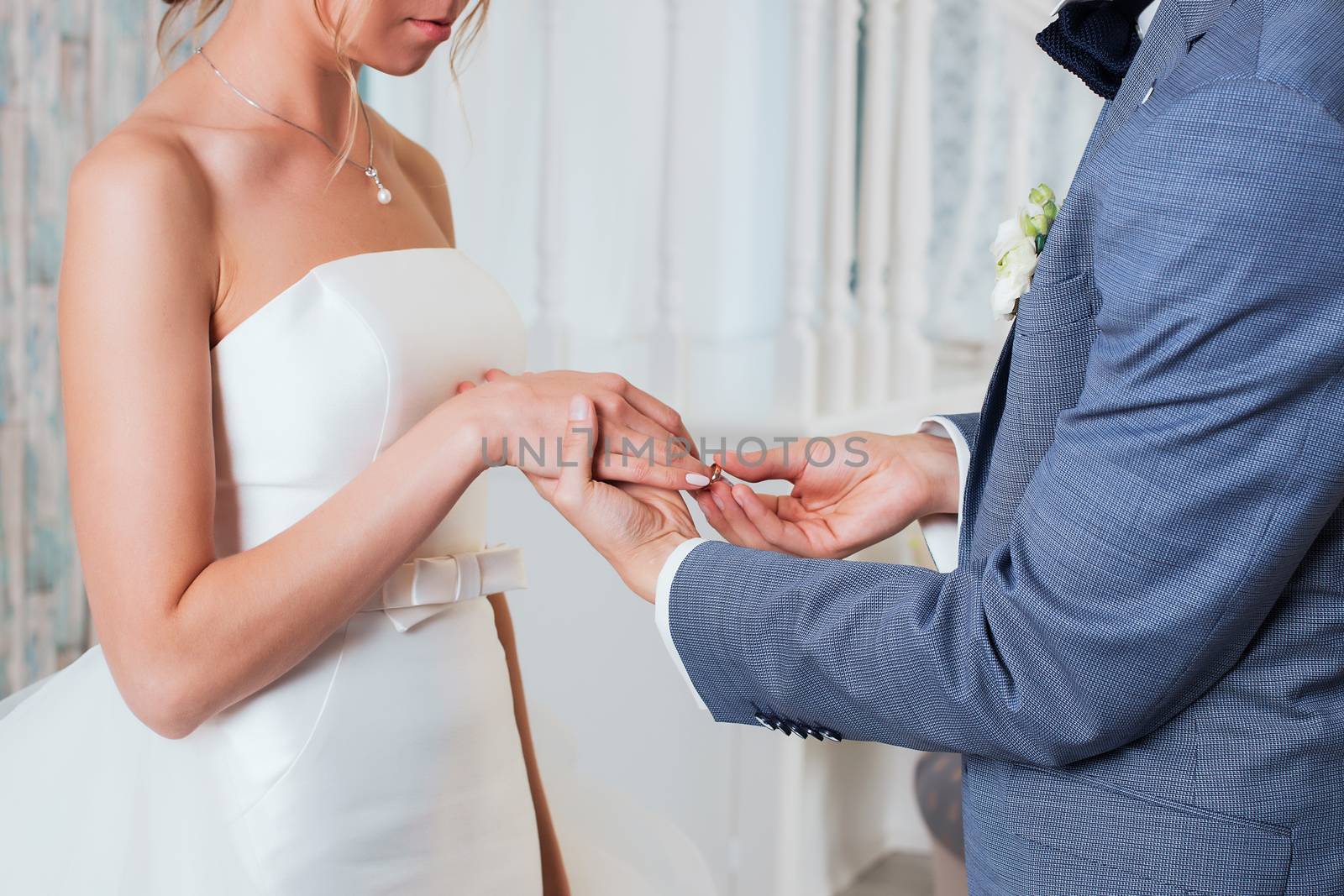 The groom places the ring on the bride's hand. Photo closeup by 3KStudio