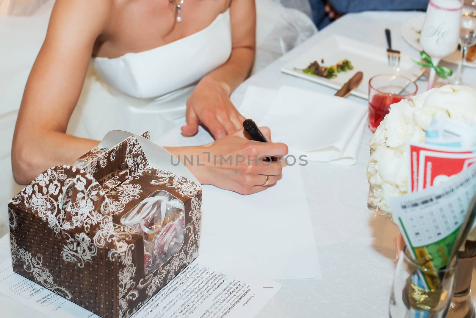 Young couple signing wedding documents. Focus on hand.