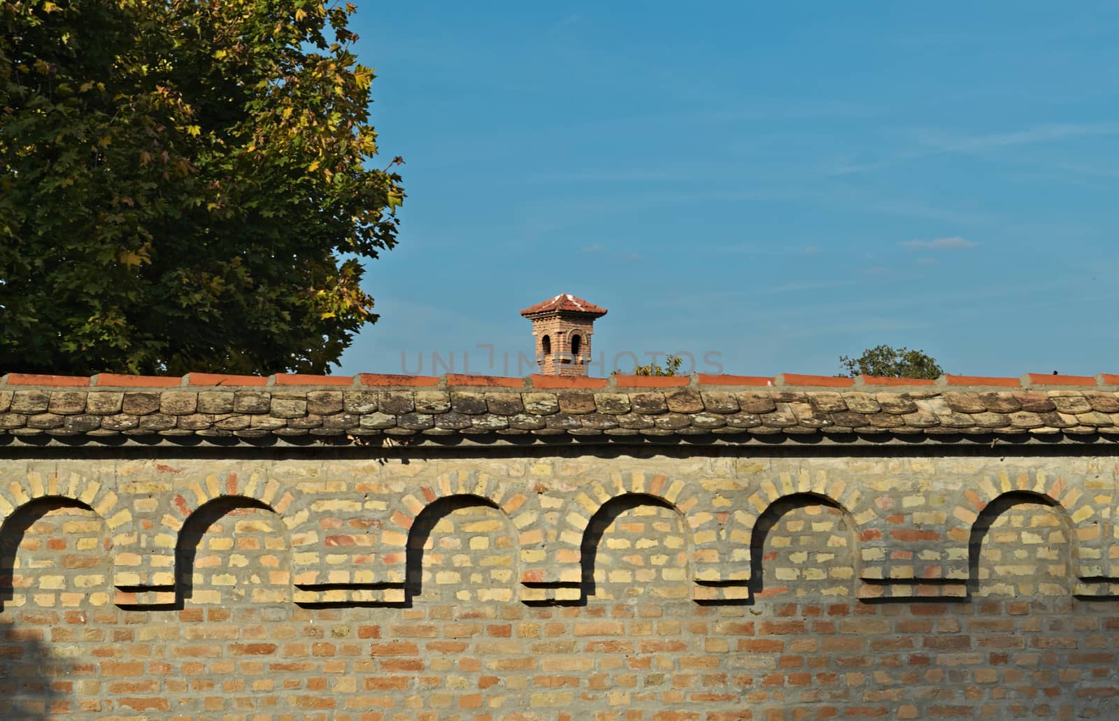 Brick wall and top of tower in center at sunny day by sheriffkule