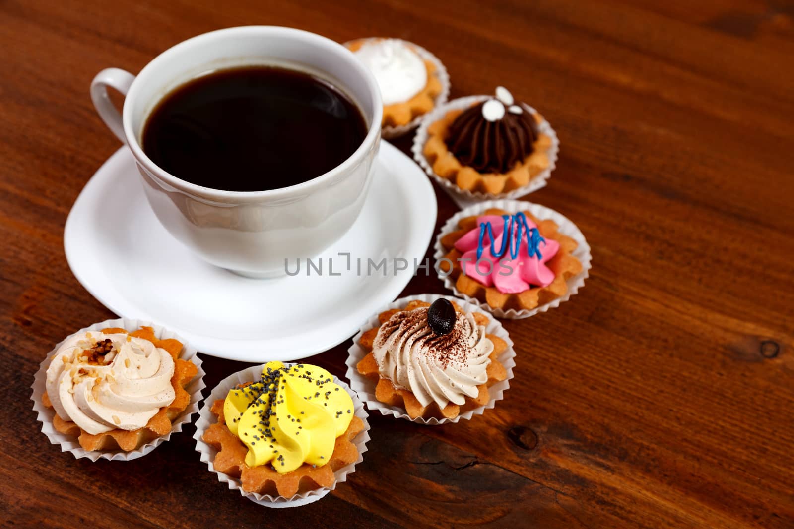 Closeup shot of small cup of coffee with colorful cupcakes by Nobilior