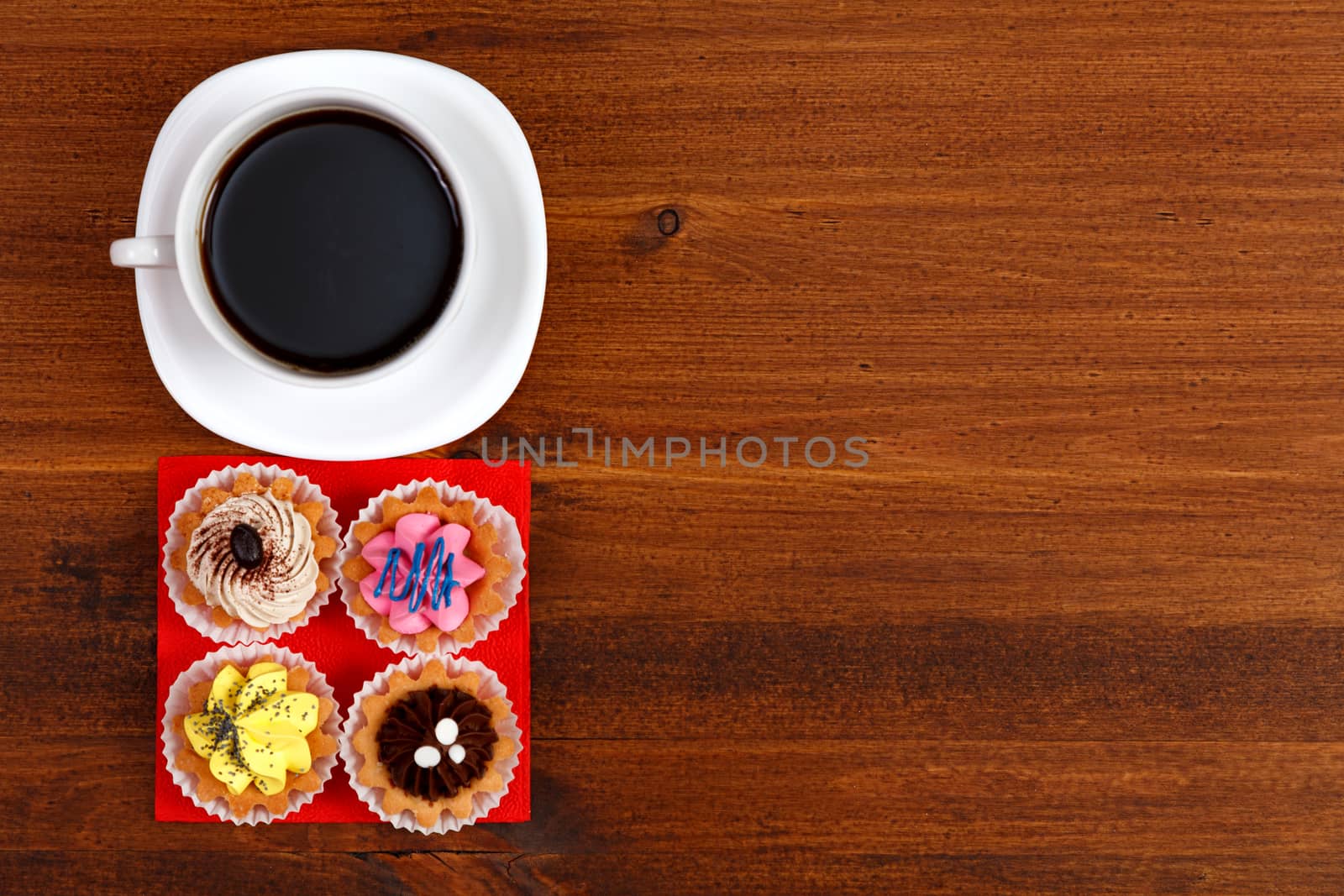 Cup of tea or coffee and four cupcakes on brown table. Top veiw