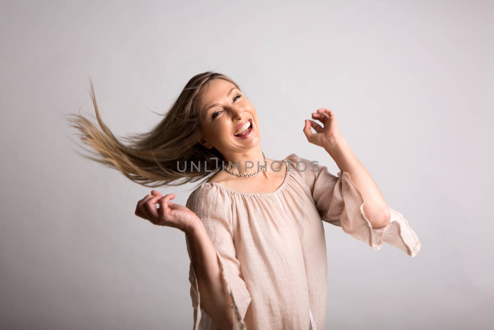 Smiling vivacious carefree woman flicking long blonde hair