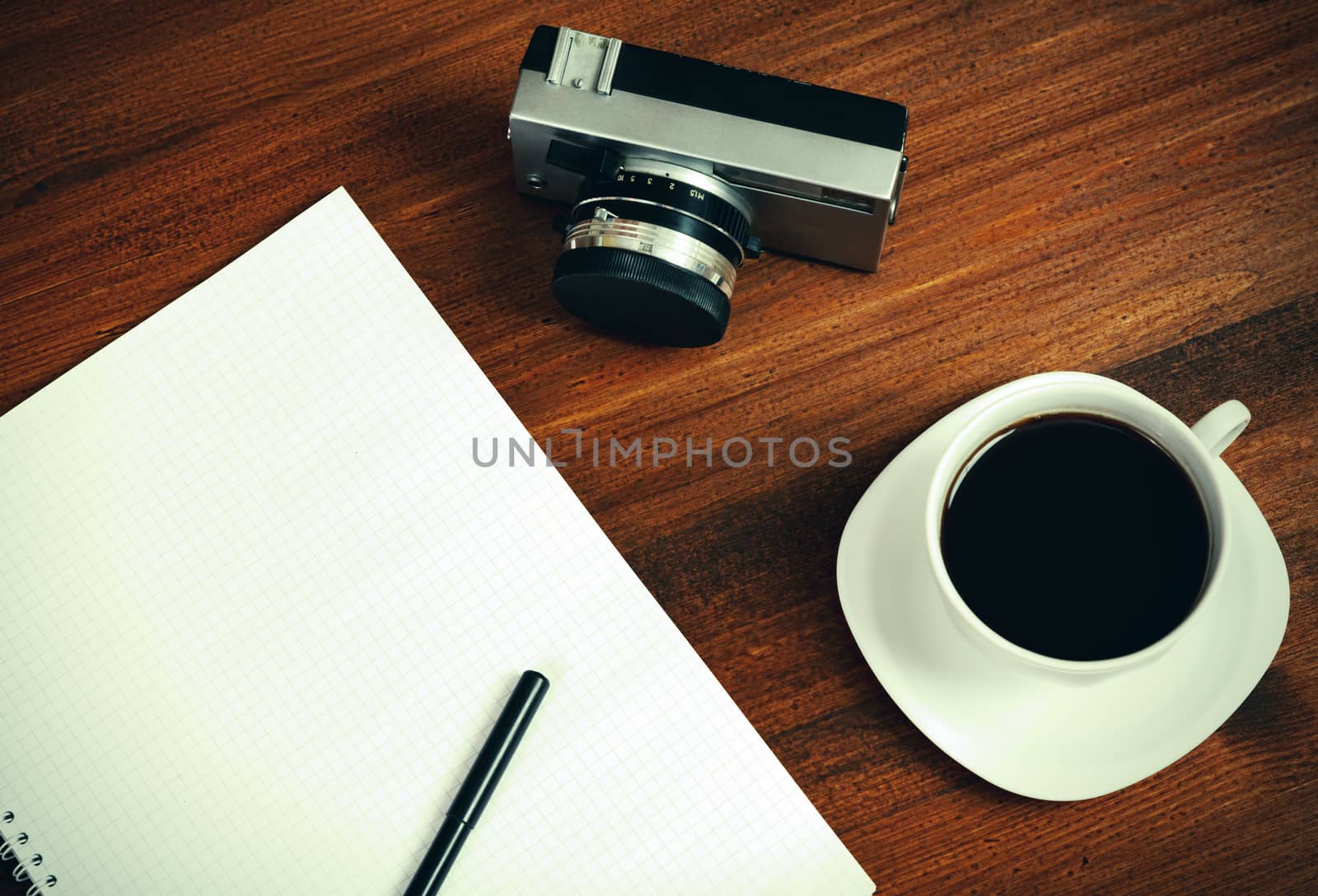 Retro film photo camera, cup of coffee and notebook with pencil by Nobilior