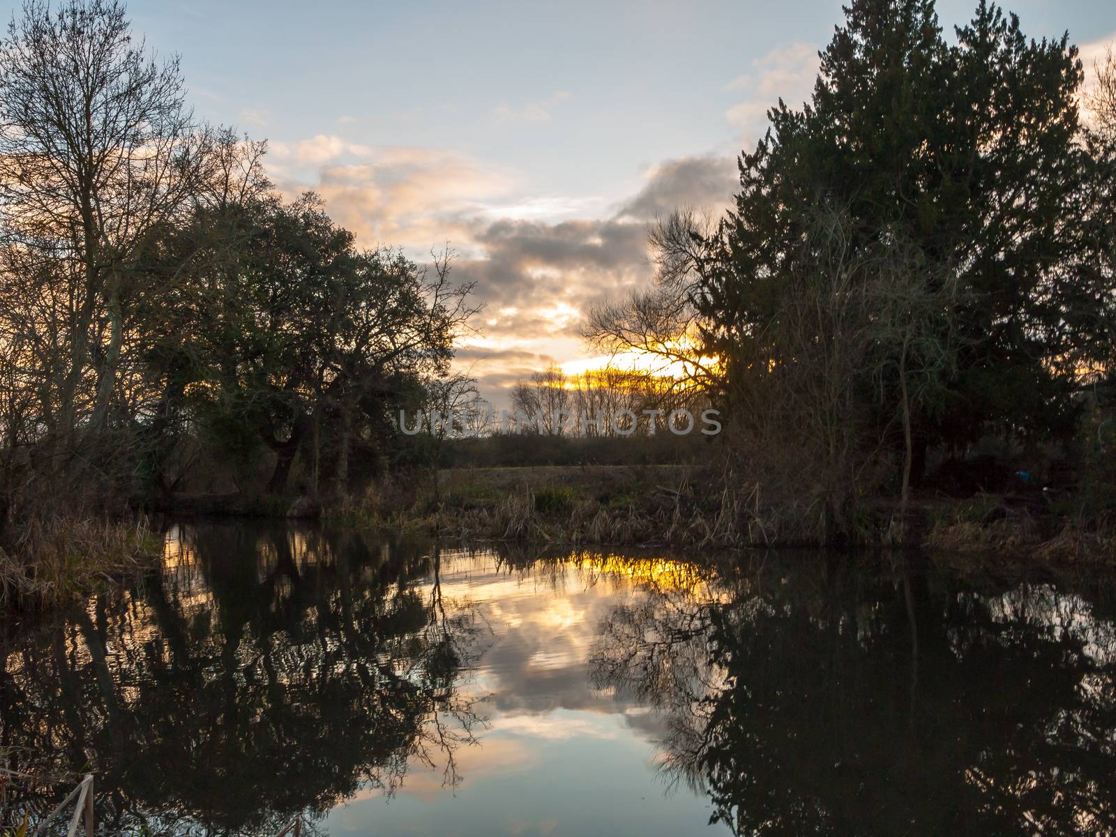 beautiful sun set autumn light sky over river trees reflections water surface; essex; england; uk