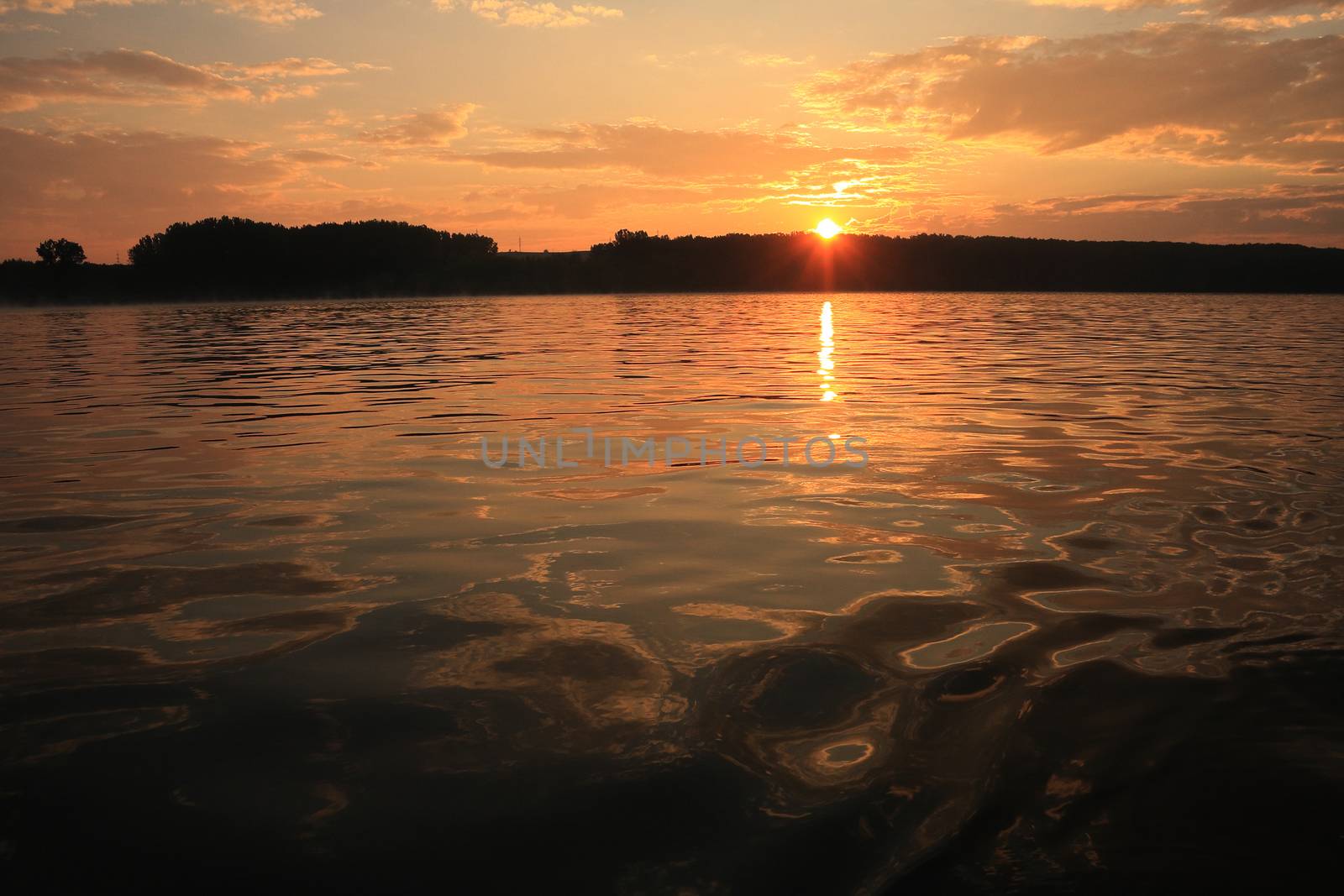 A colorful  view of a Sunset above the shore horizon viewed from a boat on the water