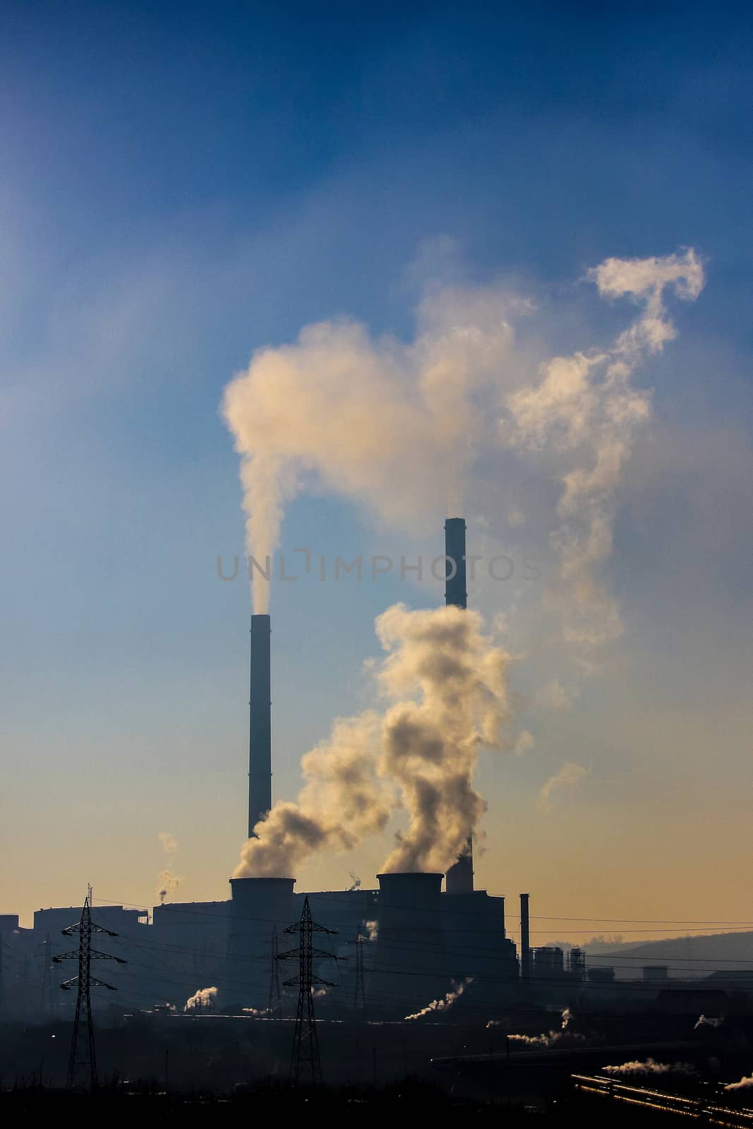 Polluting white and thick smoke coming out from four furnaces on an industrial power plant