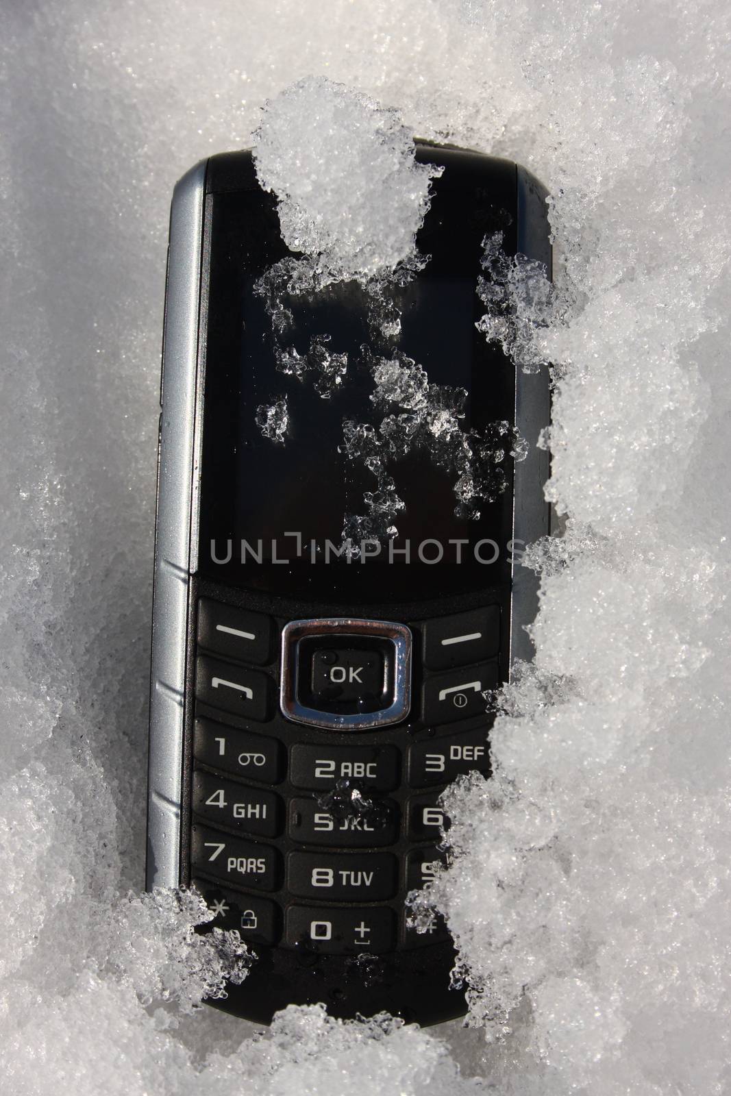 An old rugged GSM phone covered with ice 