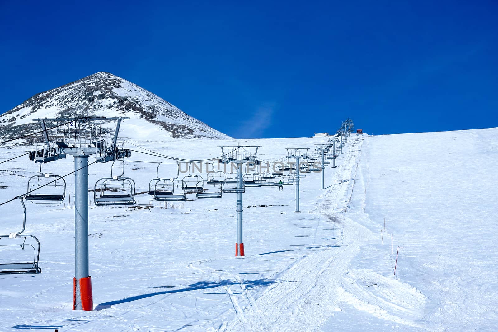 A transportation ski lift line uphill and downhill on a ski resort slope