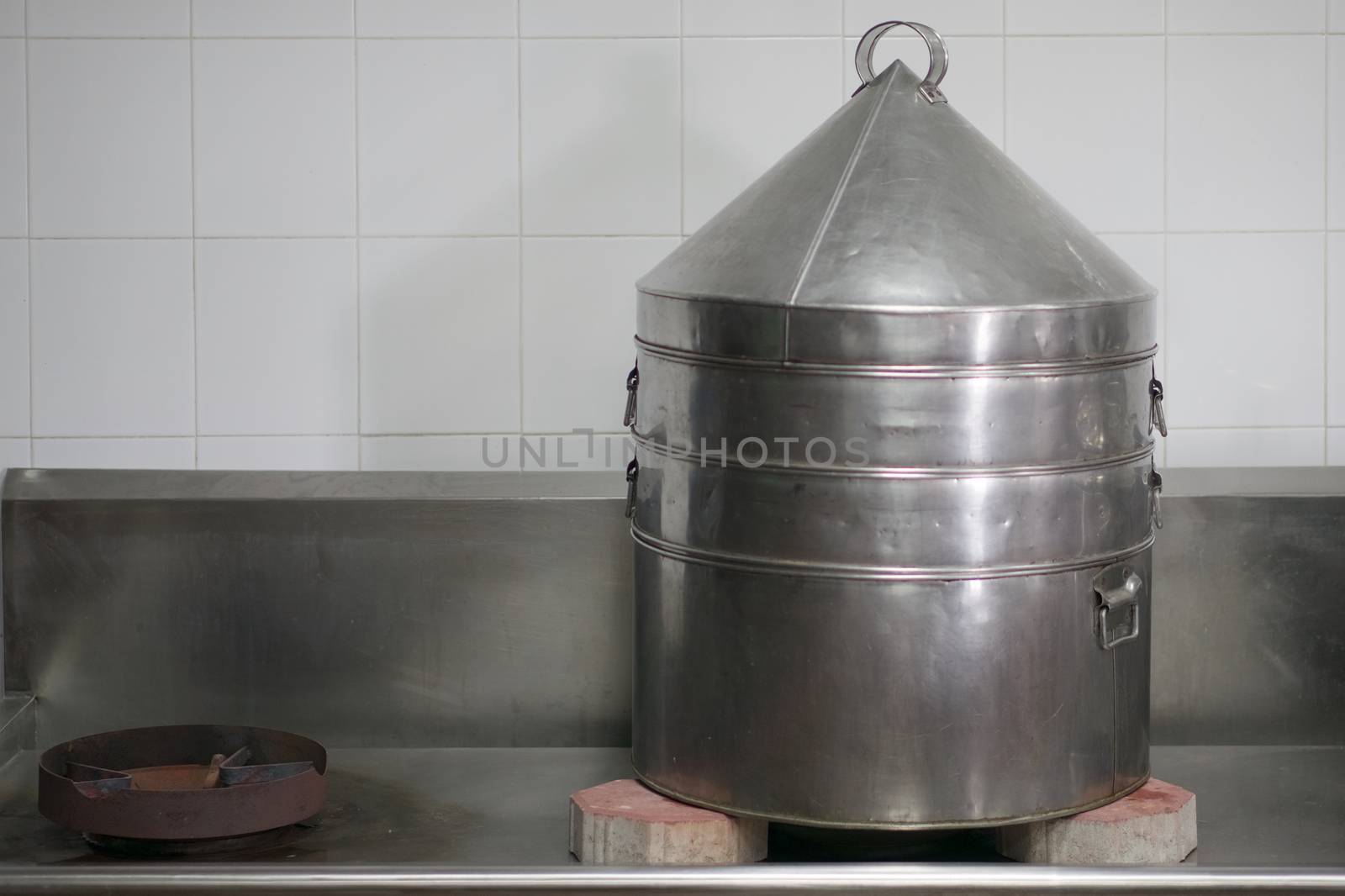 Big aluminium steamer of bun or dim sum on gas stove with red brick in restaurant kitchen with white tile on wall as background and copy space. Food and healthy concept photography.