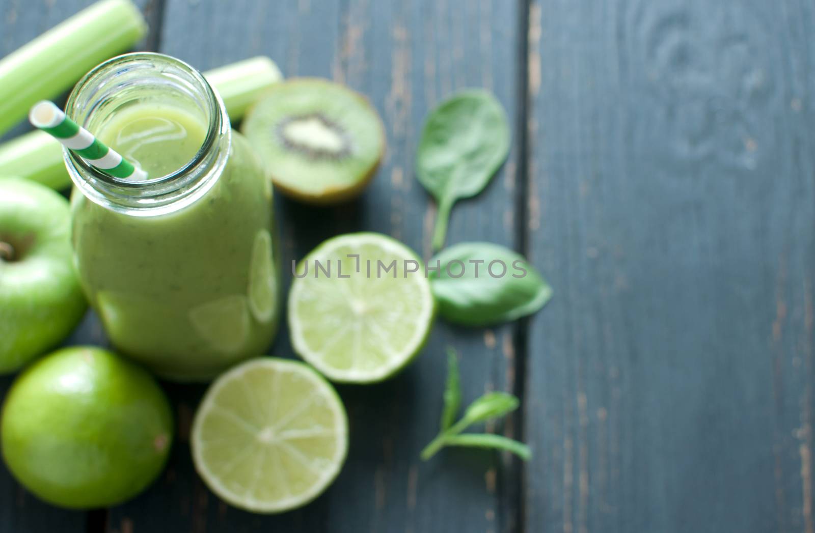 Green smoothie bottle with ingredients on wooden table