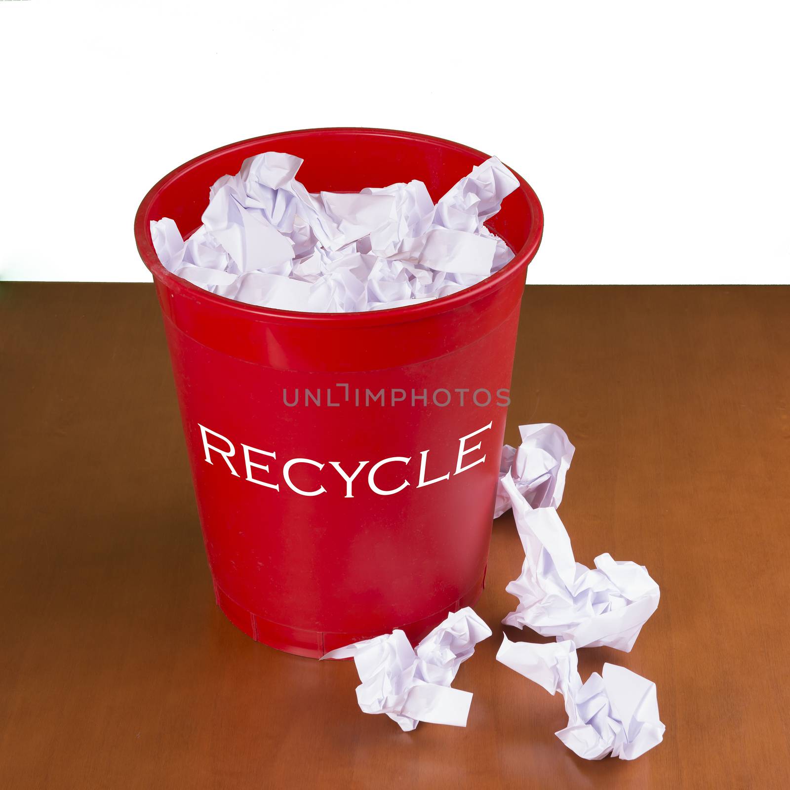 a red wastebasket for collecting waste paper