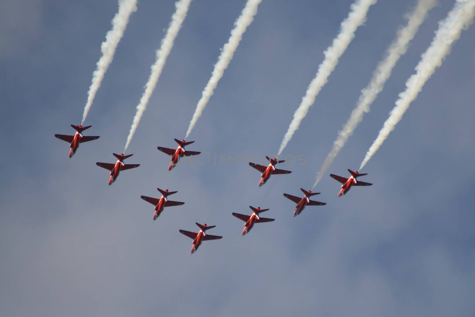 The royal air force red arrows air show flying in formation overhead in England.