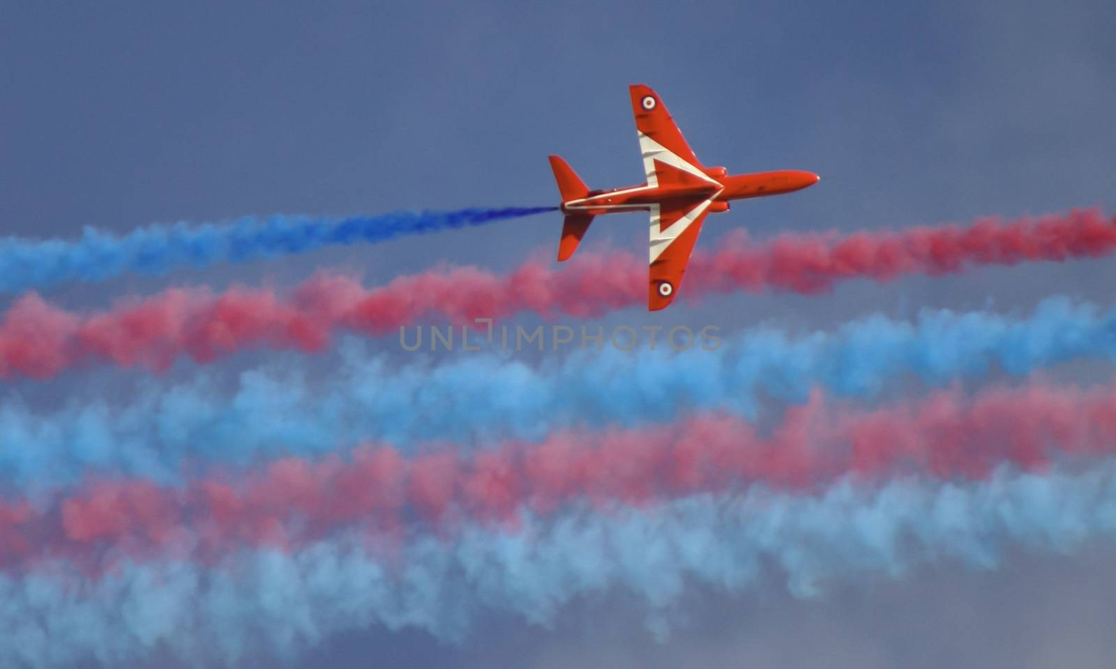 Royal air force red arrow with smoke trails part of an air display flying overhead in england.