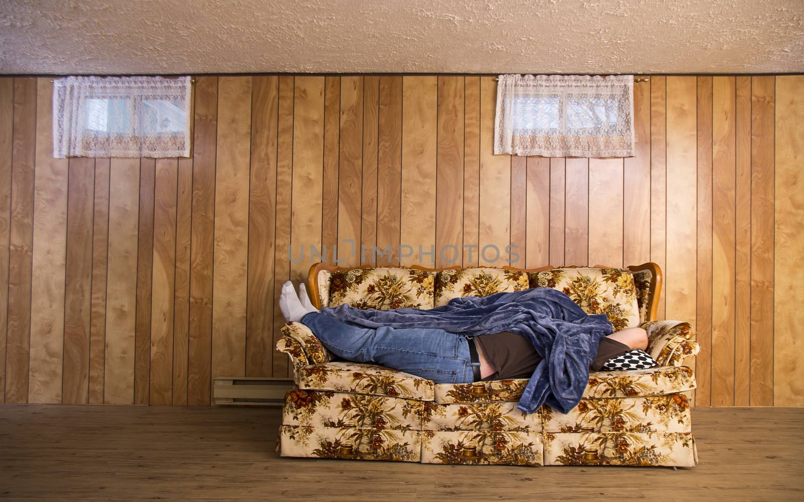 man wearing jeans, sleeping on his back, on an old basement couch