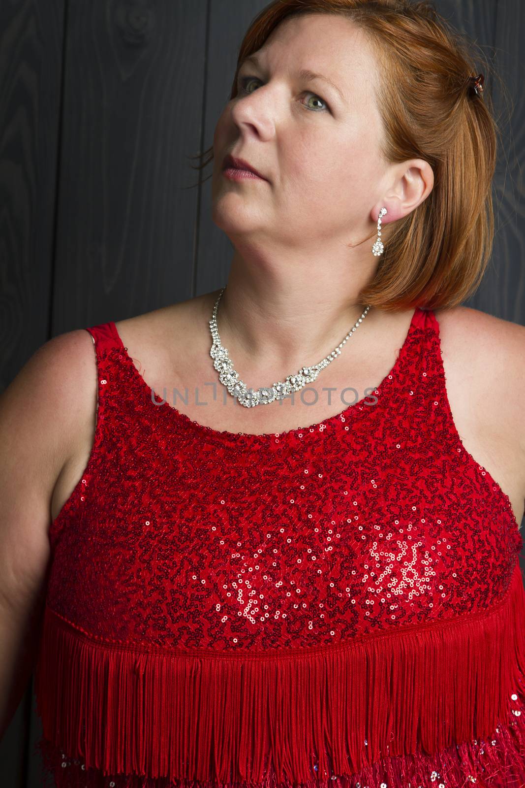 forty something large woman in sparkly dress in front of a blue wood stain background