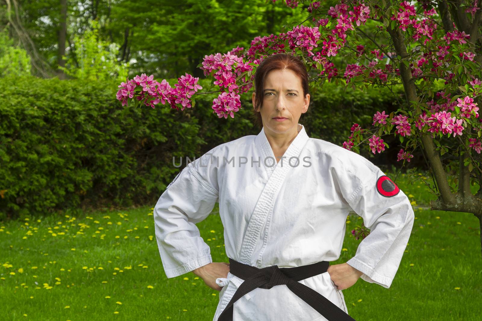 forty something brunette woman, wearing a wearing karate gi, standing under a cherry tree