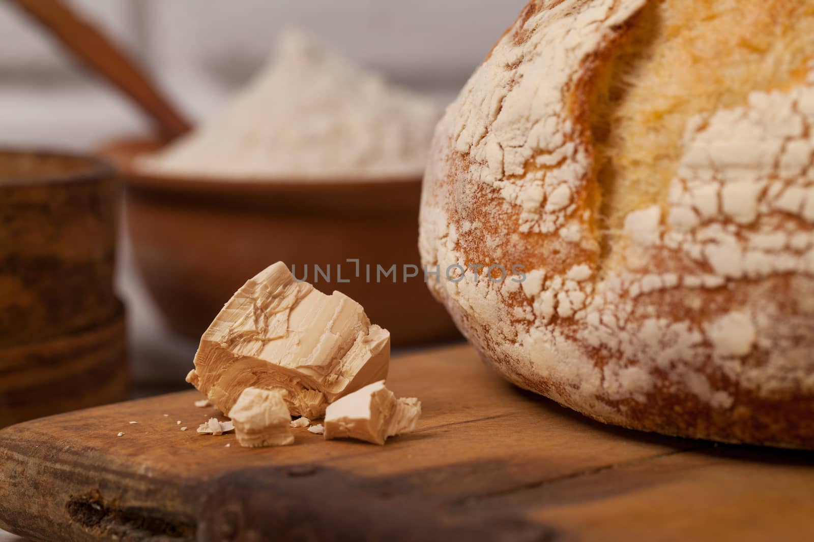 Homemade bread on old cutting board with a pile of fresh yeast by igor_stramyk