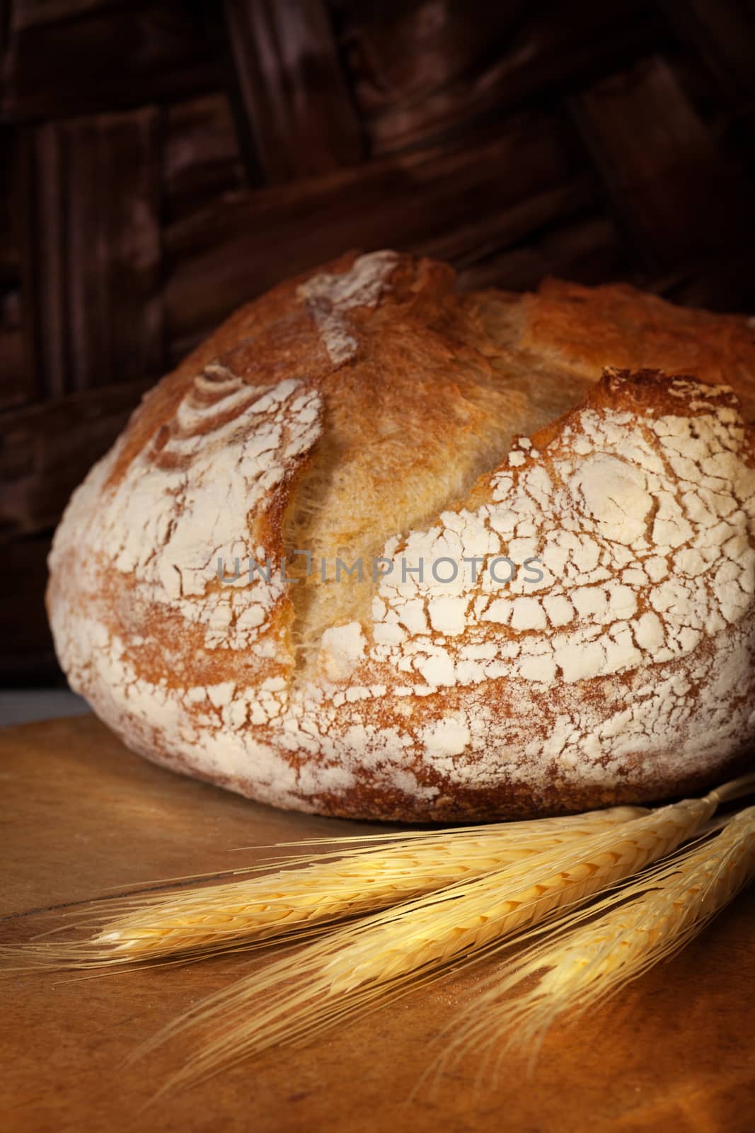 Crannied rustical homemade bread loaf on old cutting board. Dark background.