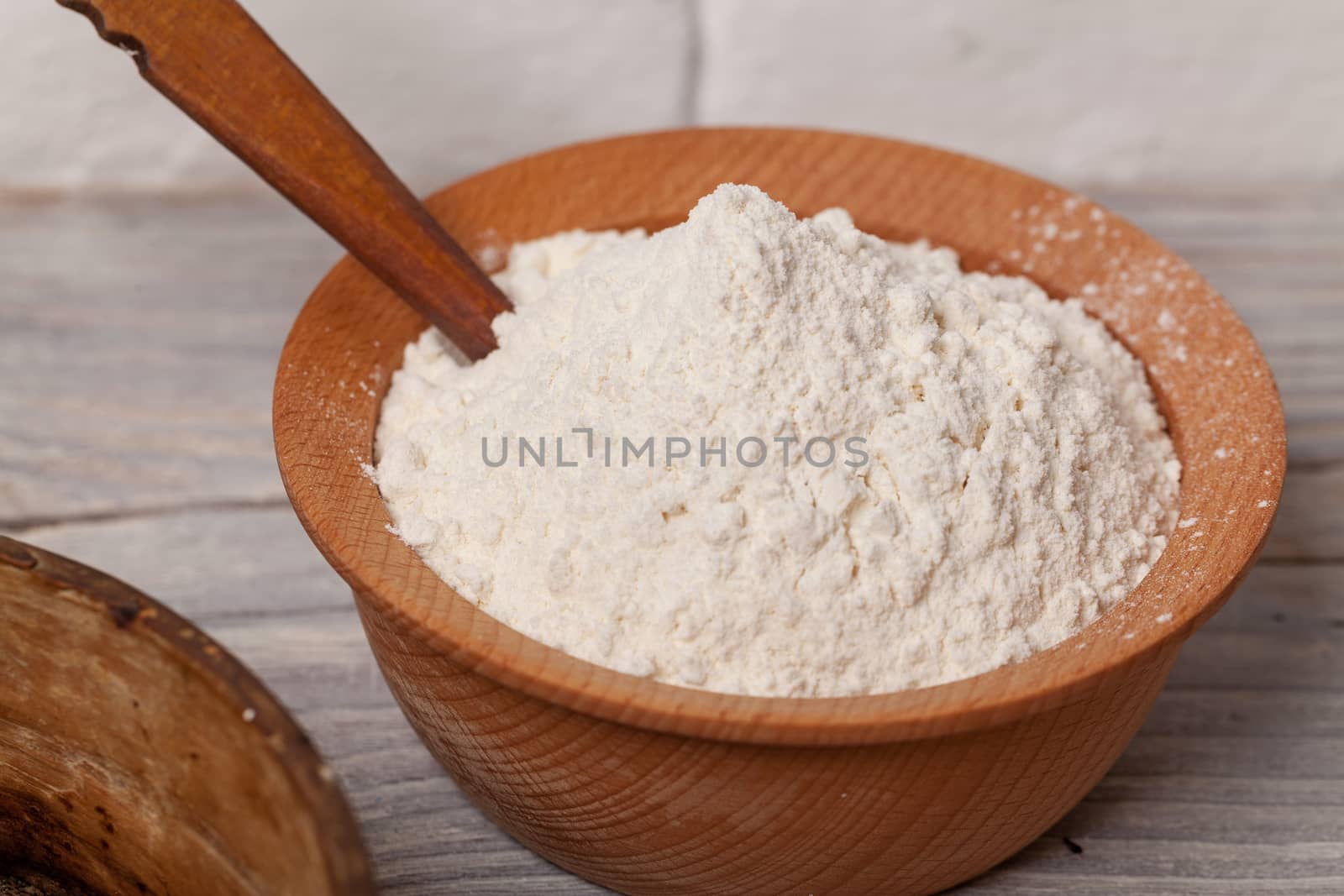 Wheat flour in wooden bowl with wooden spoon
