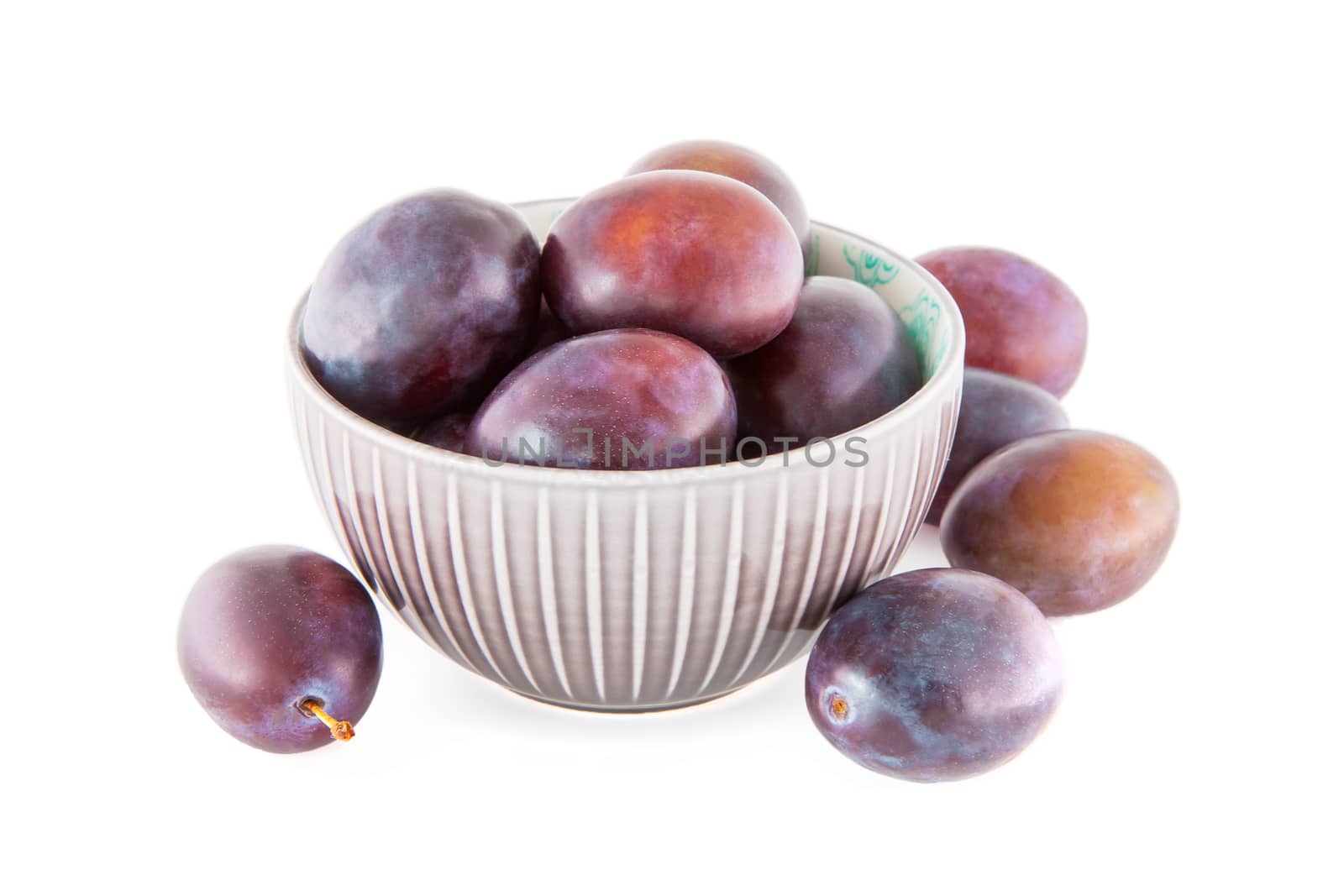 Fruits, plums in a porcelain bowl isolated on white