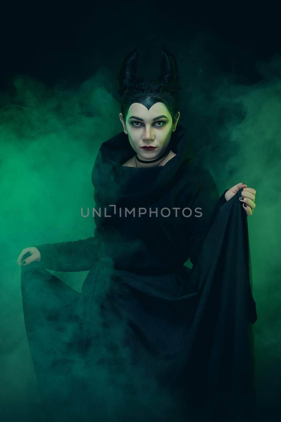 Maleficent demonic - starring. Beautiful woman from a fairytale with hair horns outdoor. Beautiful girl with horns dressed up as devil. Woman with makeup, nail polish. Fantasy. Halloween concept.