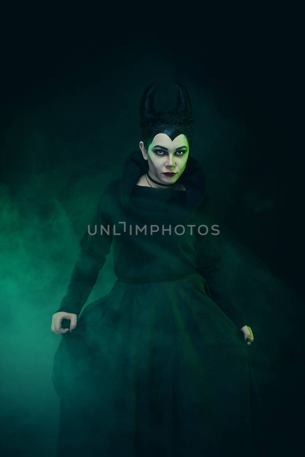 Maleficent demonic - starring. Beautiful woman from a fairytale with hair horns outdoor. Beautiful girl with horns dressed up as devil. Woman with makeup, nail polish. Fantasy. Halloween concept.