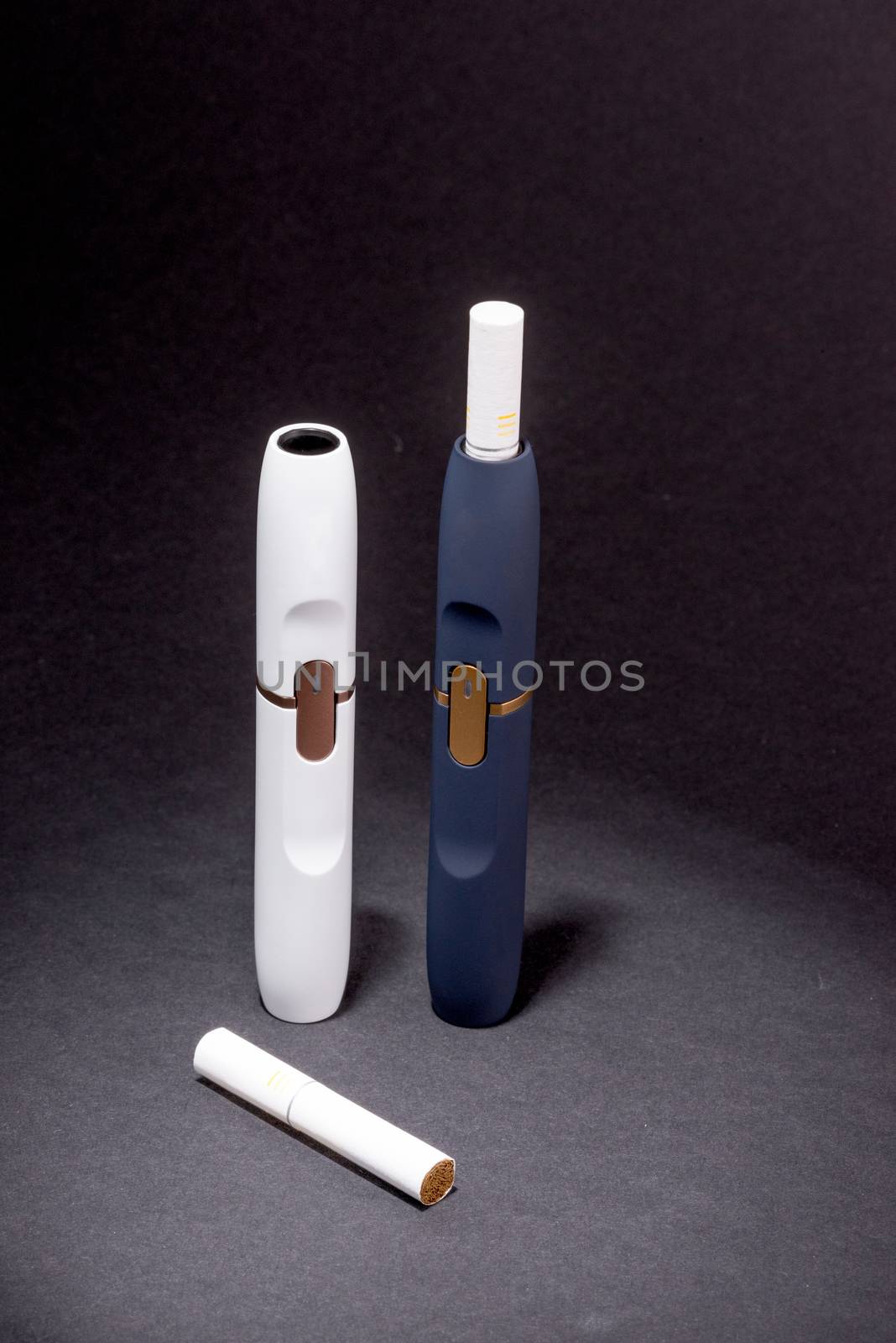 Newest electronic cigarettes, heating tobacco system IQOS, smoking, white and dark blue device isolated on black background