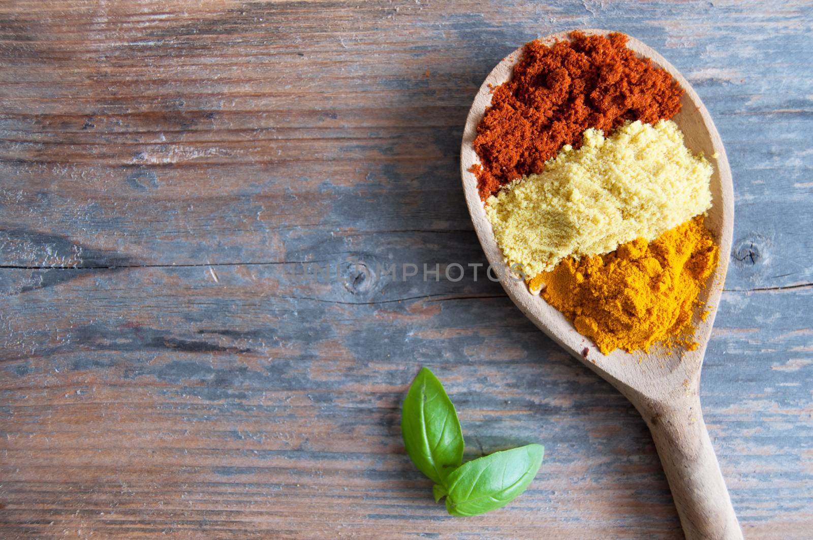 Mix of spices in a wooden spoon over a wooden background