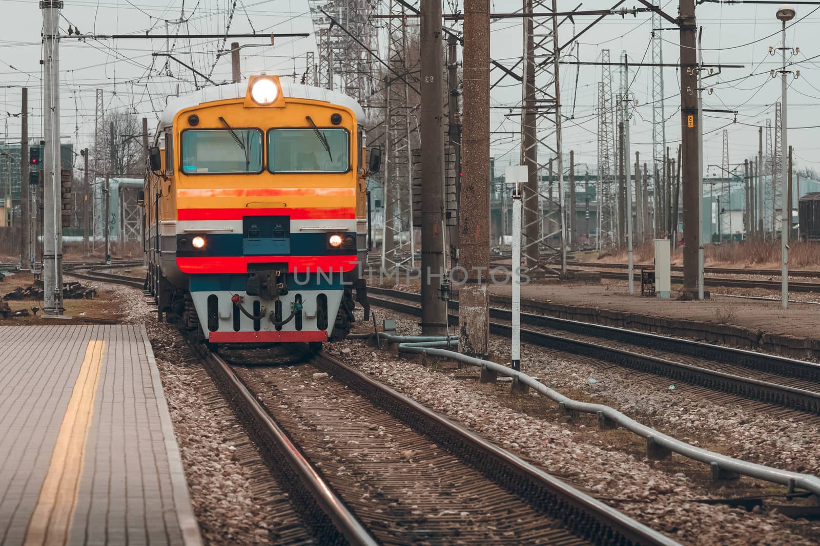 Old yellow passenger diesel train moving at the terminal